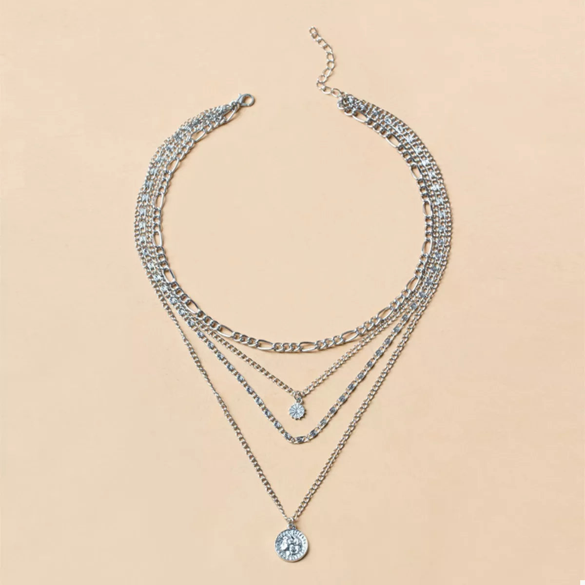 Celestial layered necklace stack with vintage coin charm and radiant sun pendant