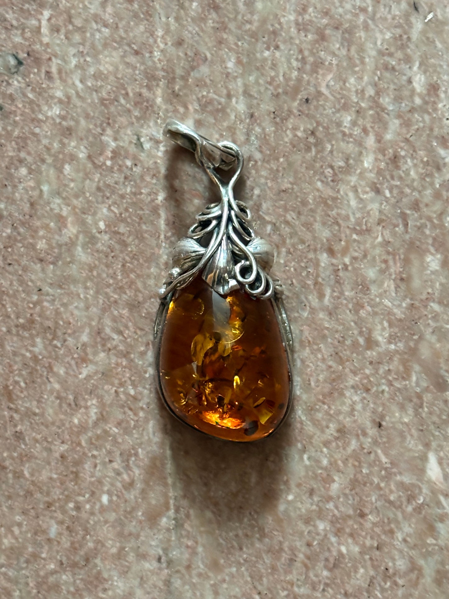 Amber pendant with silver setting on a textured surface