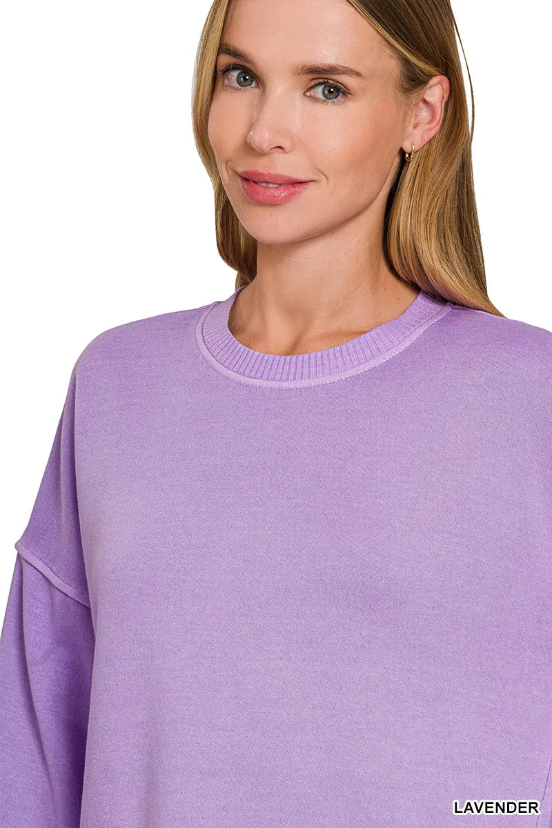 Woman wearing an oversized lavender pullover sweatshirt with contrast white stitching and balloon sleeves.