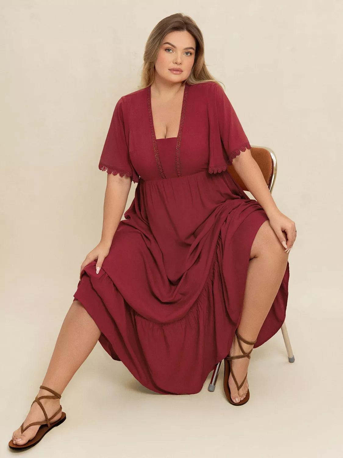 Plus-size woman wearing wine red lace trim maxi dress with flutter sleeves