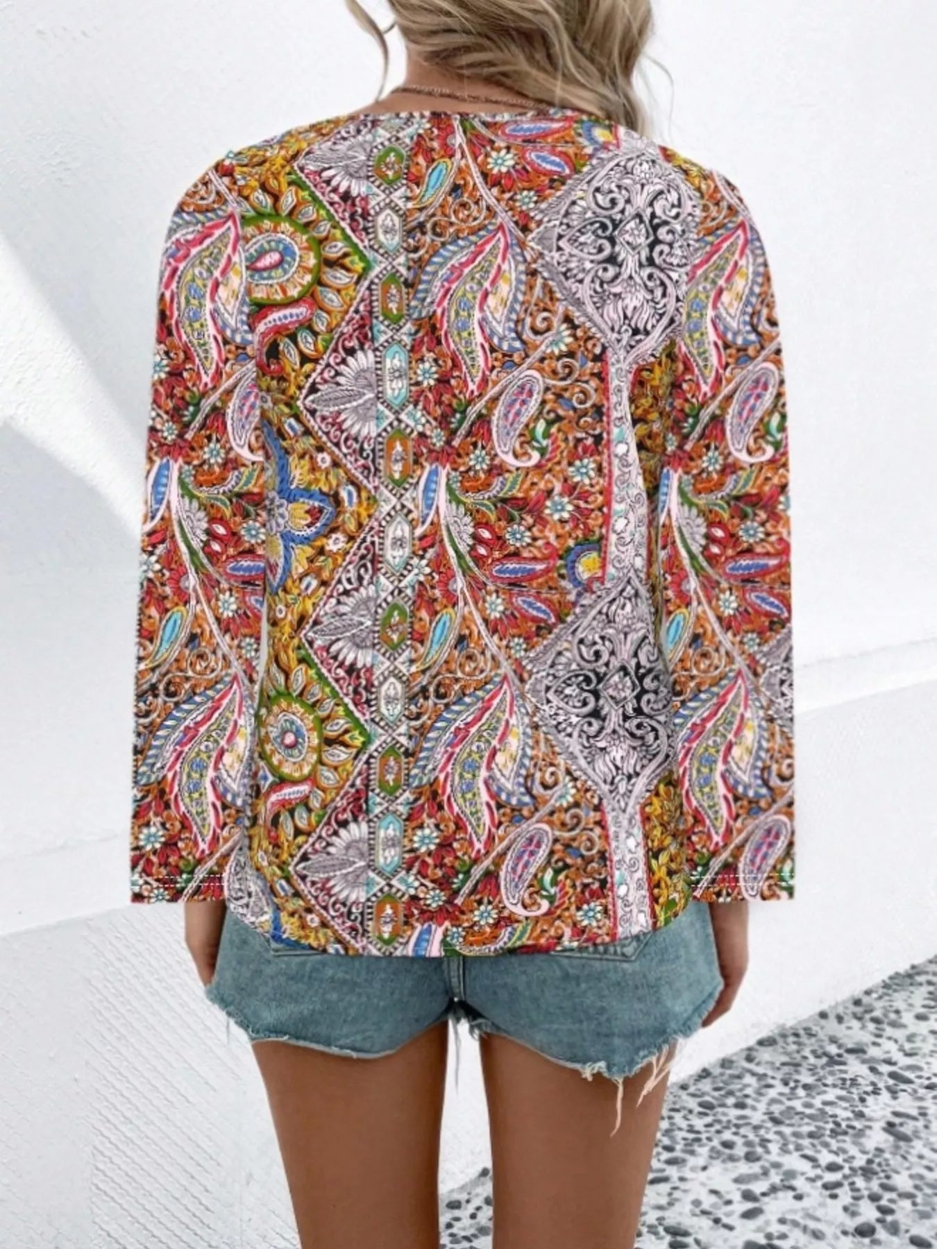 Boho paisley patchwork blouse with a V-neckline, flowy long sleeves, and relaxed slightly stretchy fit styled with denim shorts.