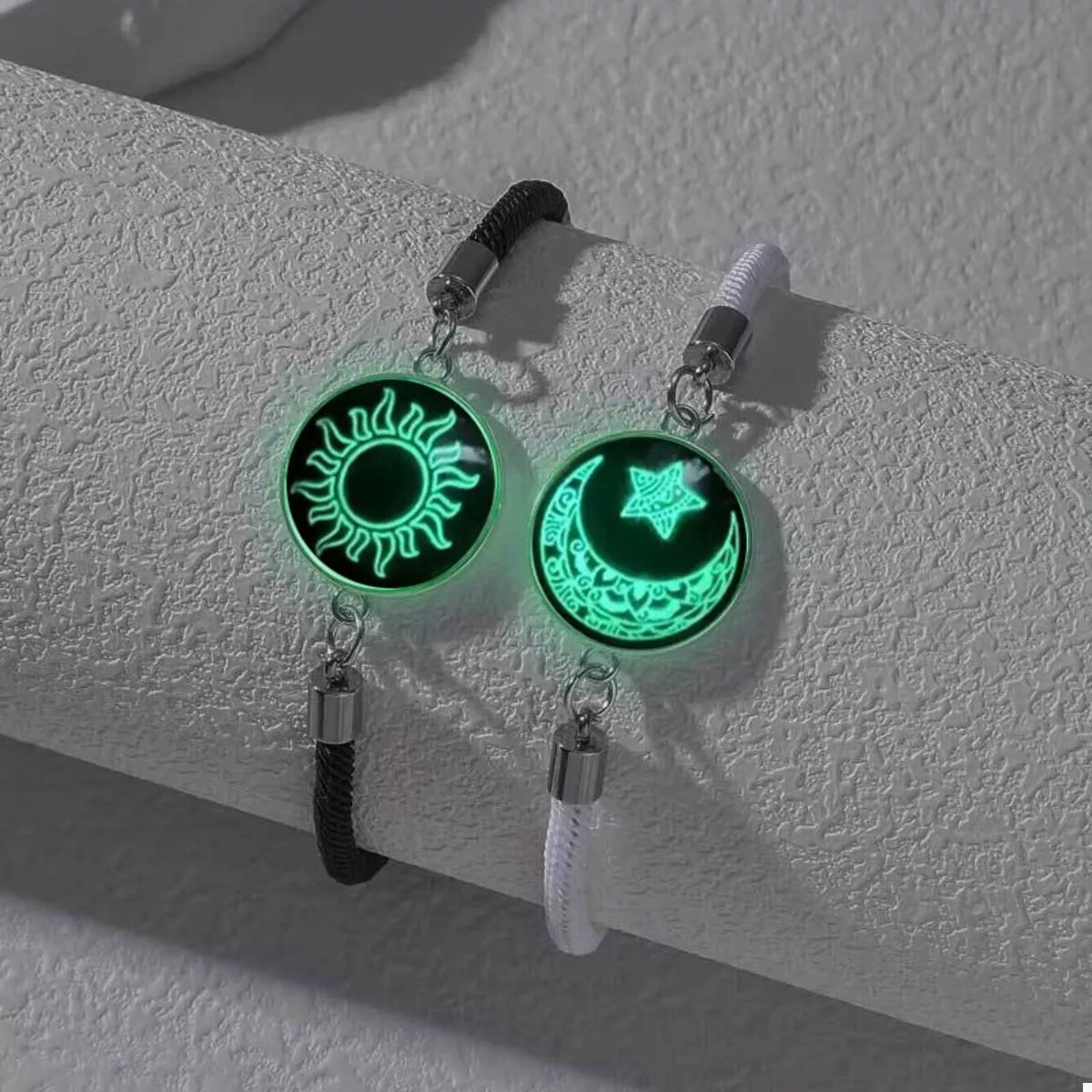 Two-piece glow-in-the-dark bracelet set with sun and moon charms on black braided rope bands