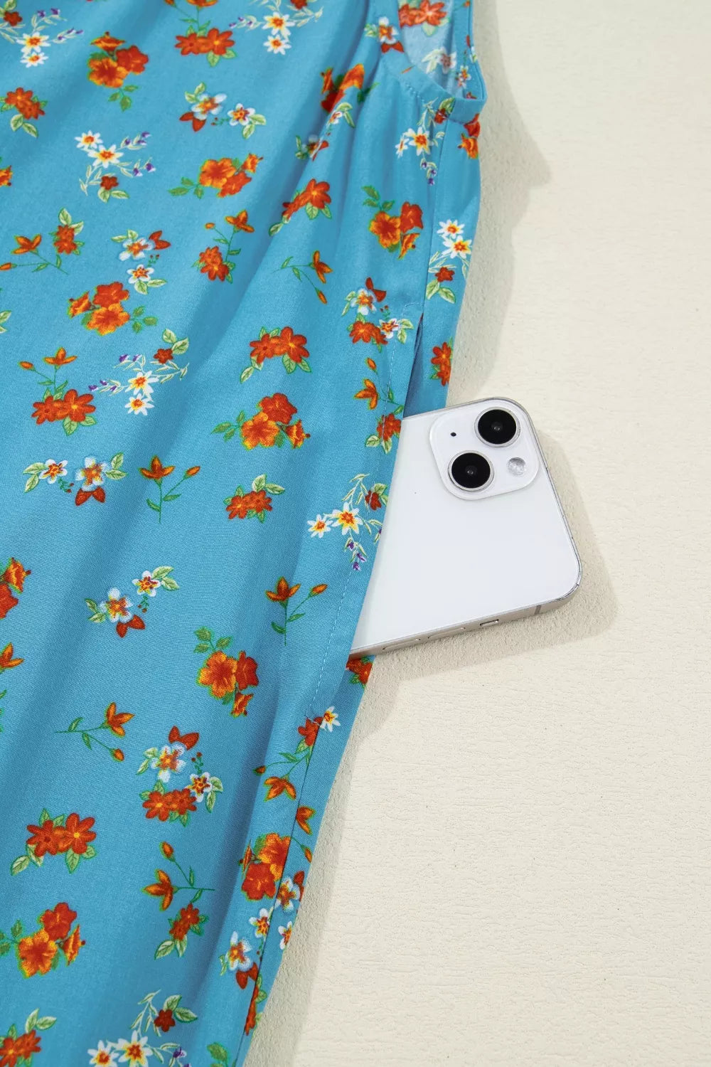 Blue floral wide-leg jumpsuit with thin straps, relaxed flowy fit, and side pockets styled with sandals.