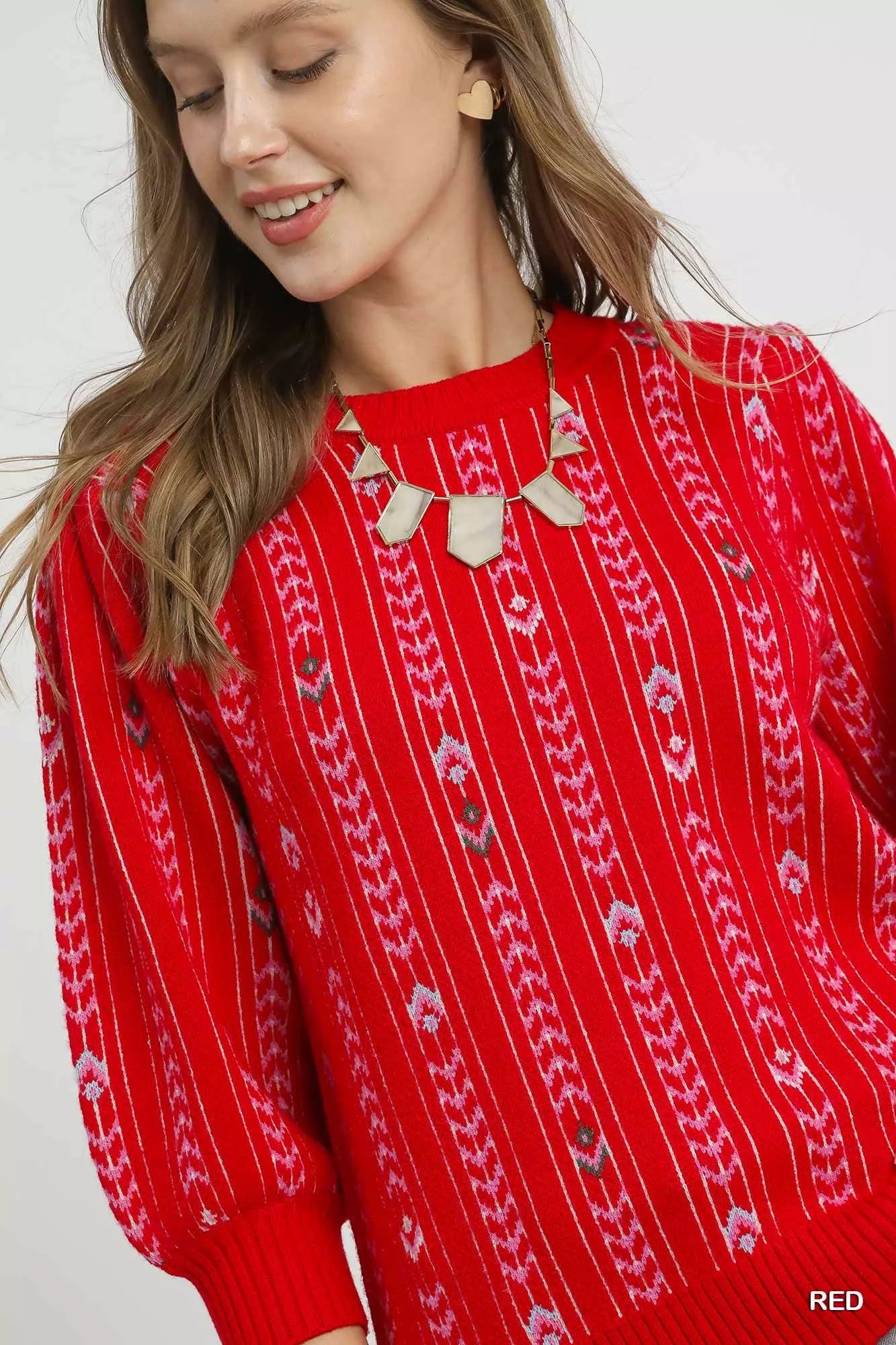 Woman wearing the Crimson Cascade Sweater in bold red with jacquard knit pattern and puff sleeves.