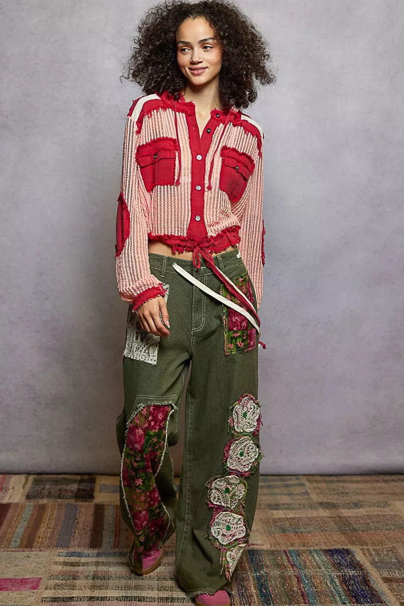 Model wearing a red and pink woven hooded button-down shirt with patch pockets and drawstring hem, styled with boho pants.