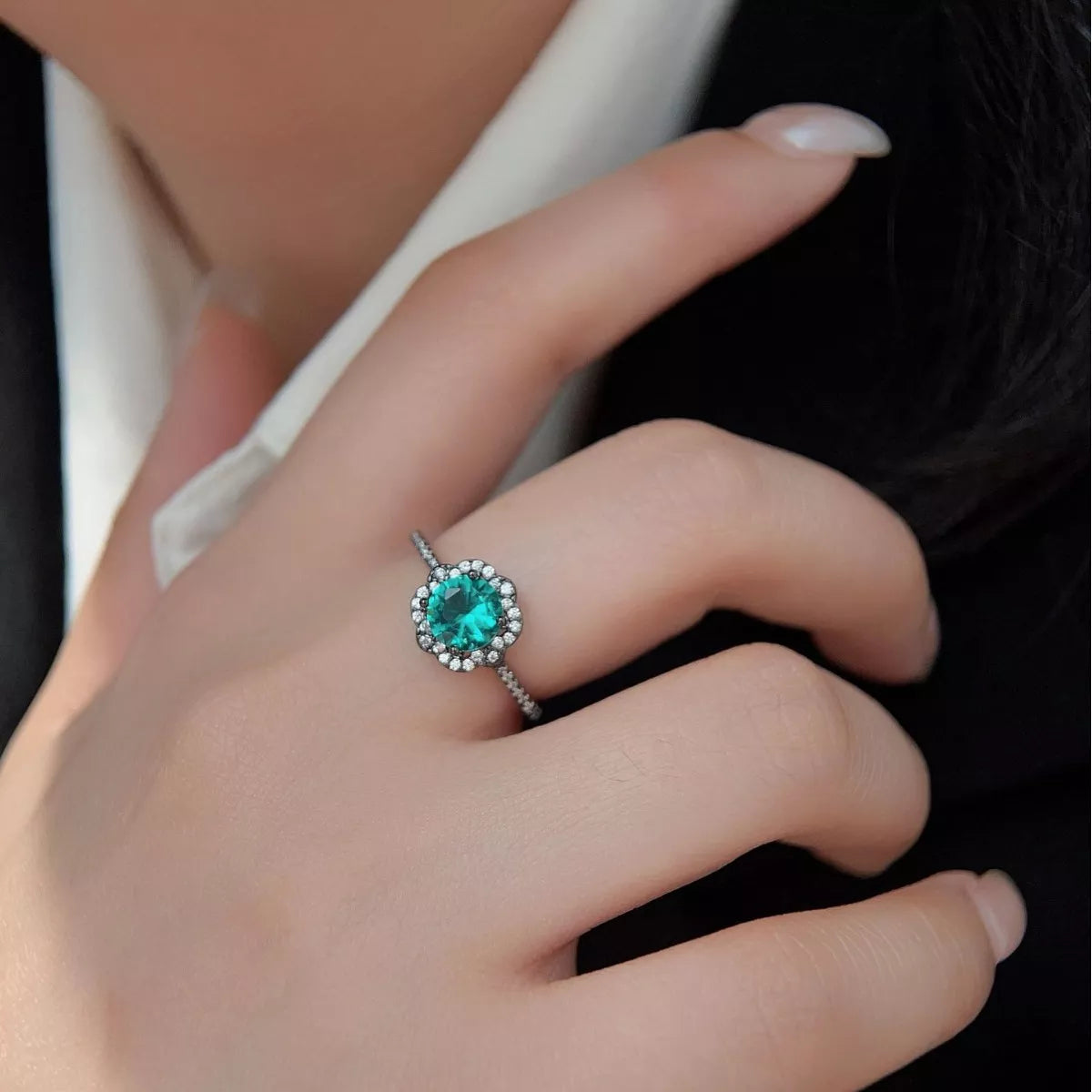 Sterling silver ring with teal center stone and zircon floral halo detailing.