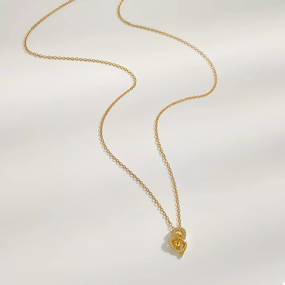 Close-up of woman wearing a gold-plated heart-shaped zircon necklace on a delicate chain, styled with a brown ribbed top for an elegant look.