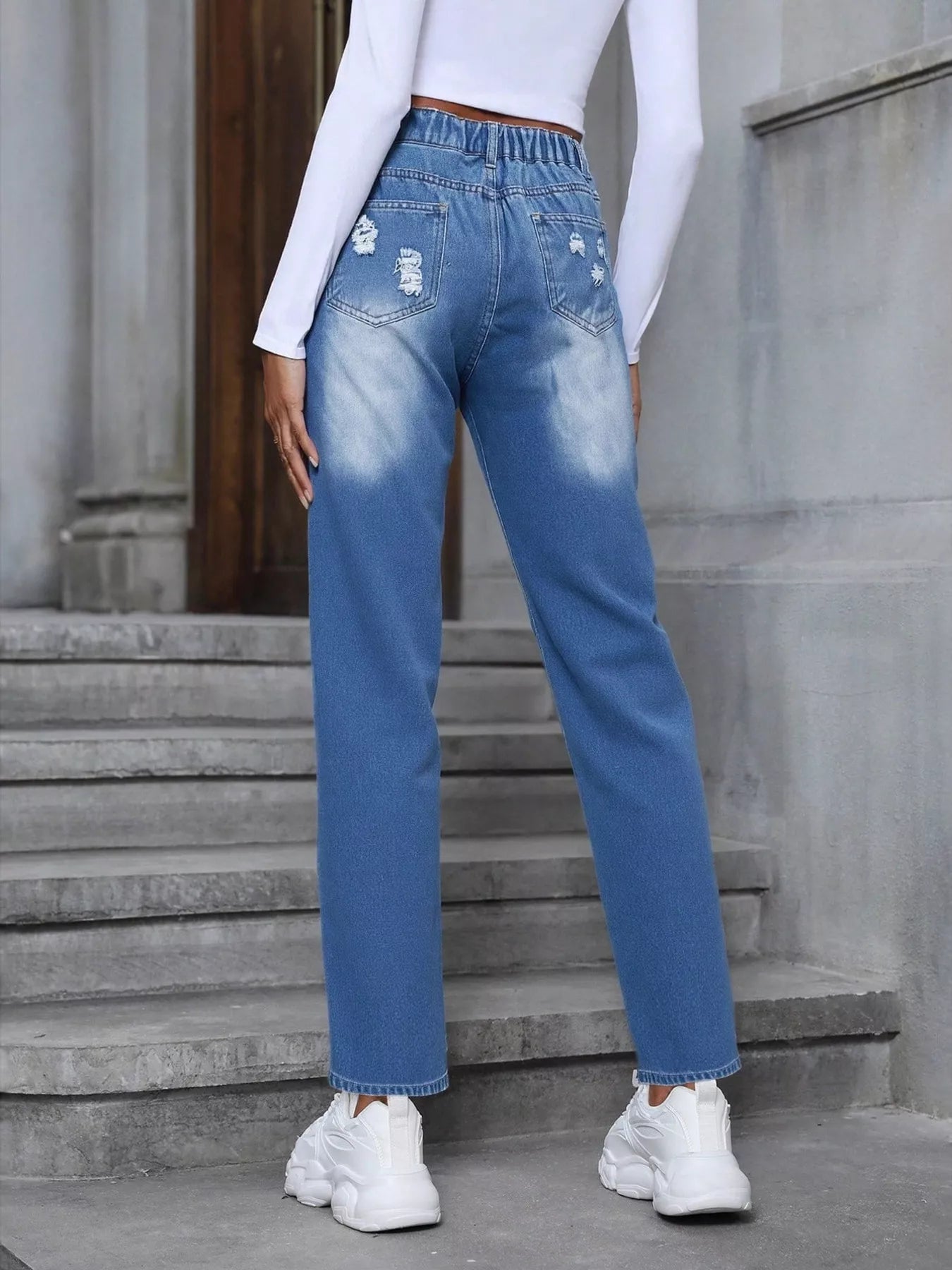 Light blue distressed high-waist jeans with colorful embroidered floral appliqué patches.