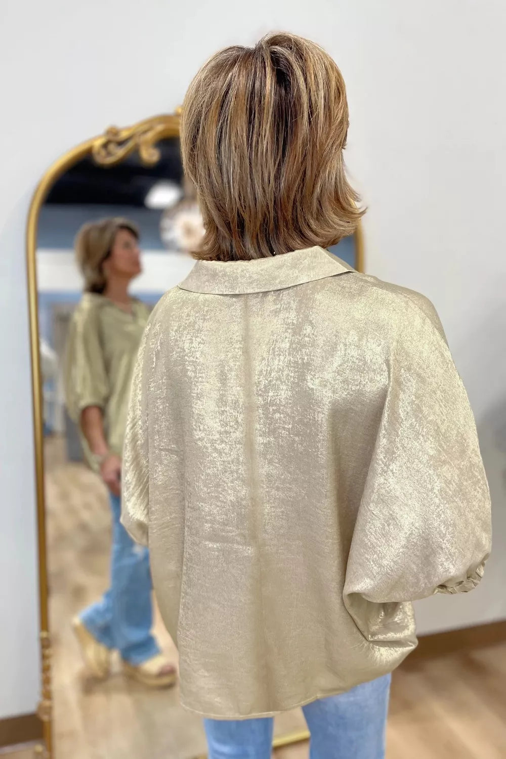 Shimmery collared puff sleeve top with a split neckline, relaxed fit, and satin-like finish styled with white pants.