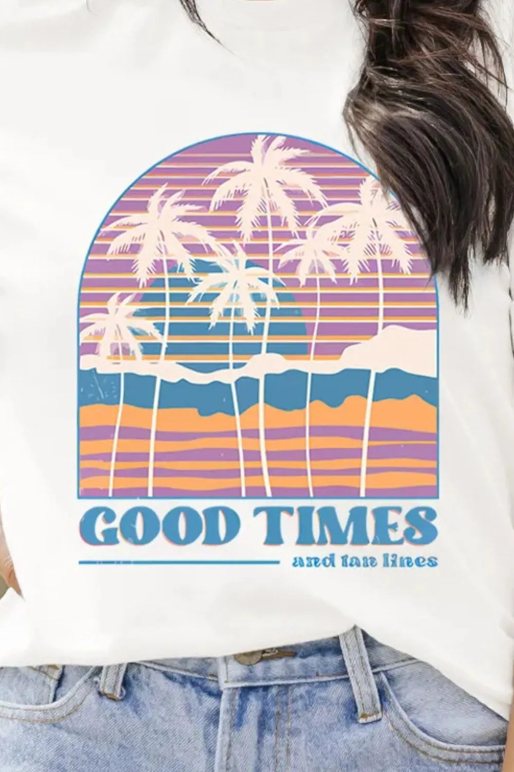 Retro palm tree sunset graphic tee with colorful stripe design styled with denim