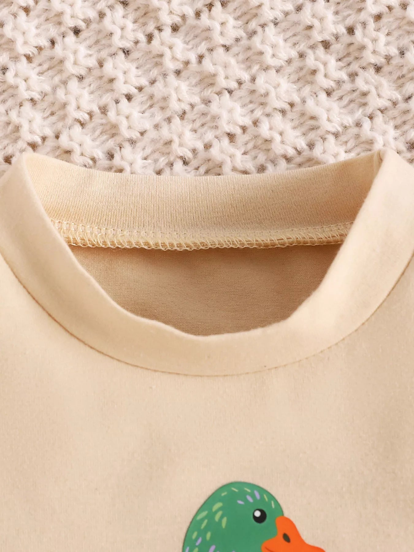 Cream baby romper with “Goose on the Loose” duck graphic, short sleeves, snap bottom, and soft cotton-blend fabric.