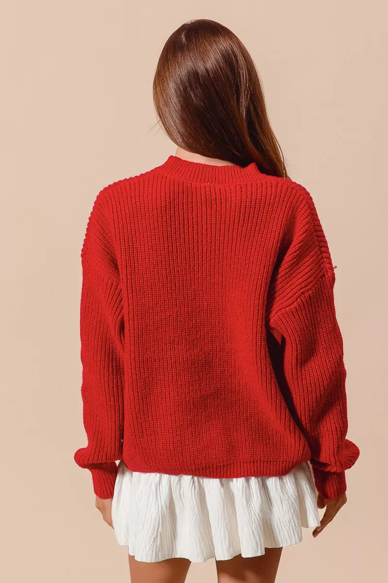 Woman wearing a red ribbed sweater with gold sequin bow designs — festive holiday sweater from A Whimsical Affair.