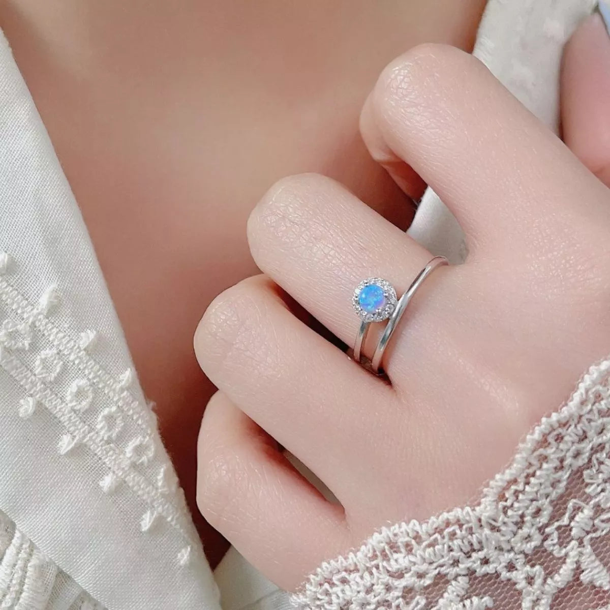 Dainty sterling silver opal ring with zircon halo and double wrap band.