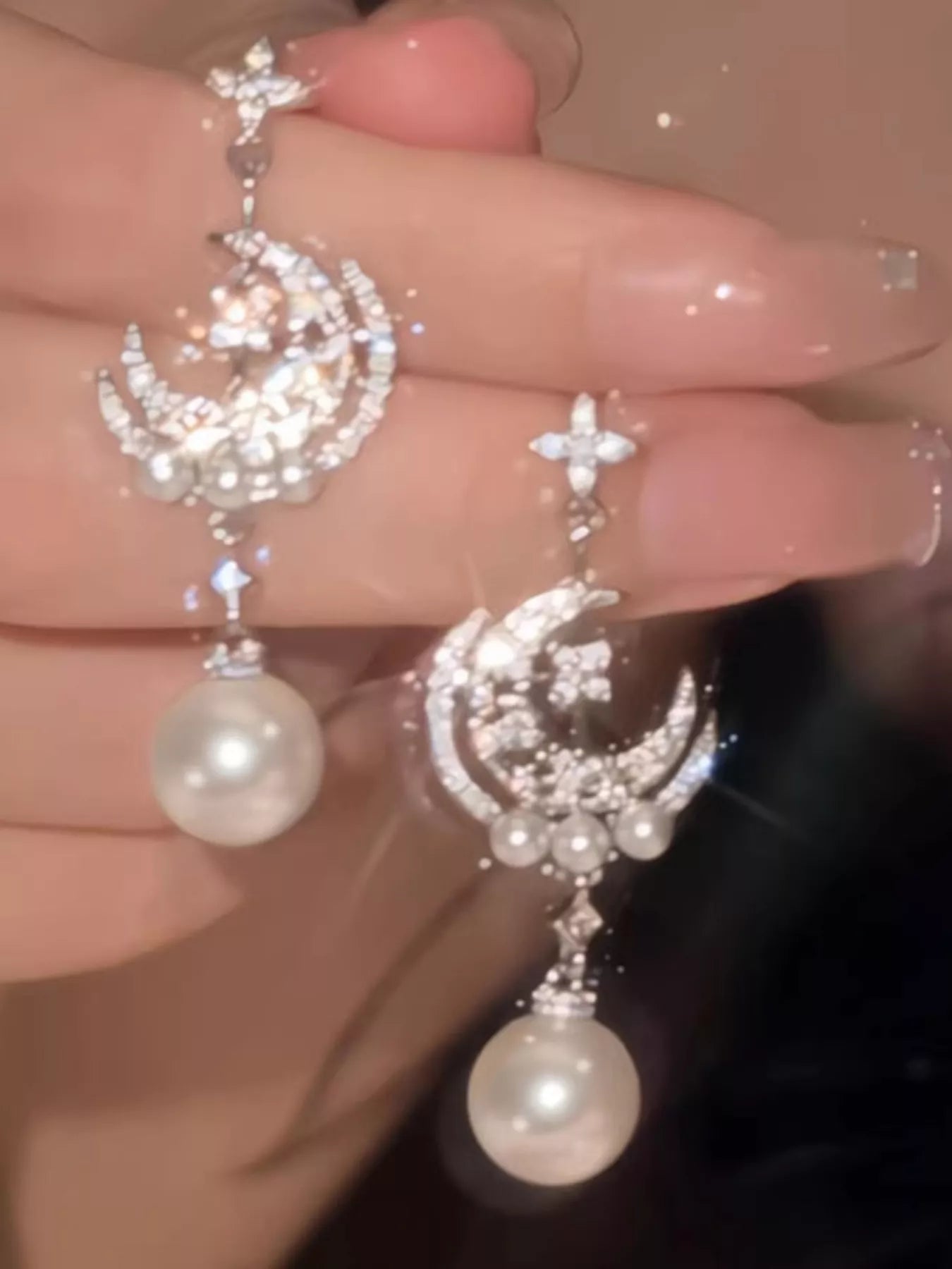 Silver celestial dangle earrings with crescent moon charms, zircon star accents, and synthetic pearl drops worn on the ear.
