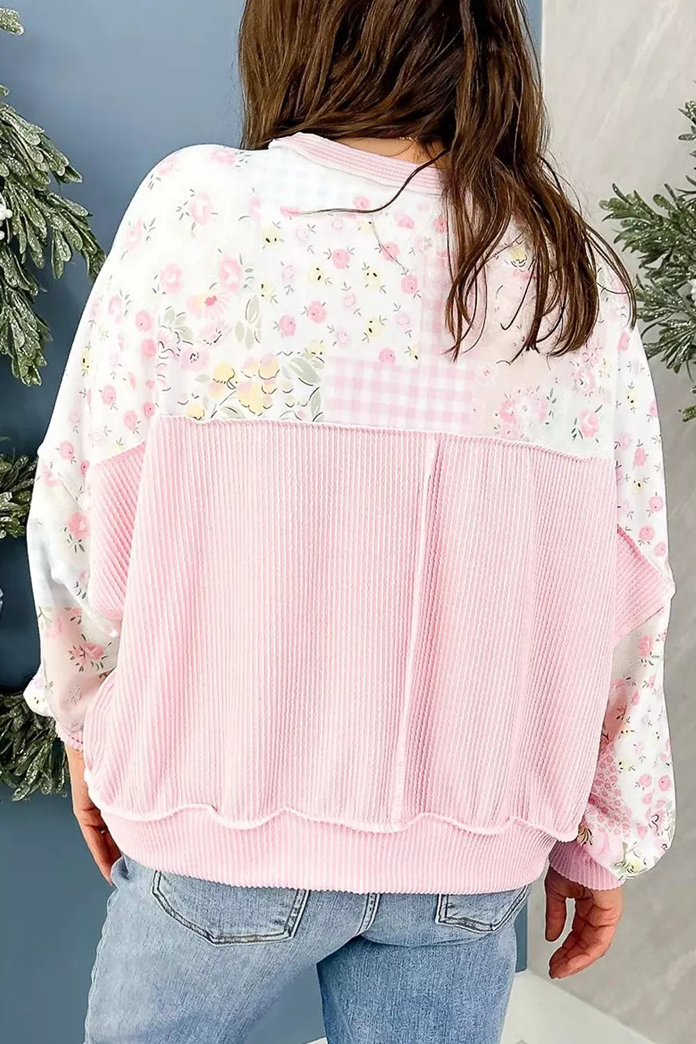 Floral patchwork pullover with soft pink ribbed trim, relaxed sweatshirt-style fit, long sleeves, and slightly stretchy fabric styled with denim.