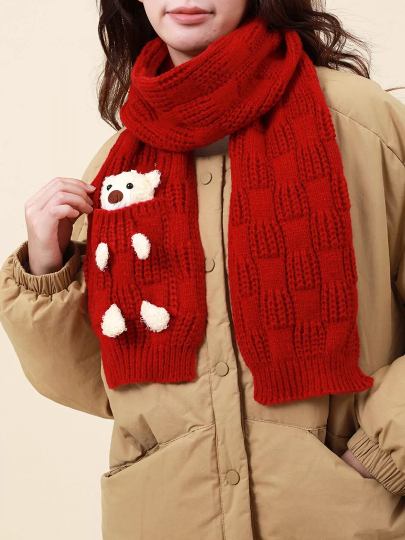 Knit winter scarf with teddy bear pocket detail worn over a jacket.