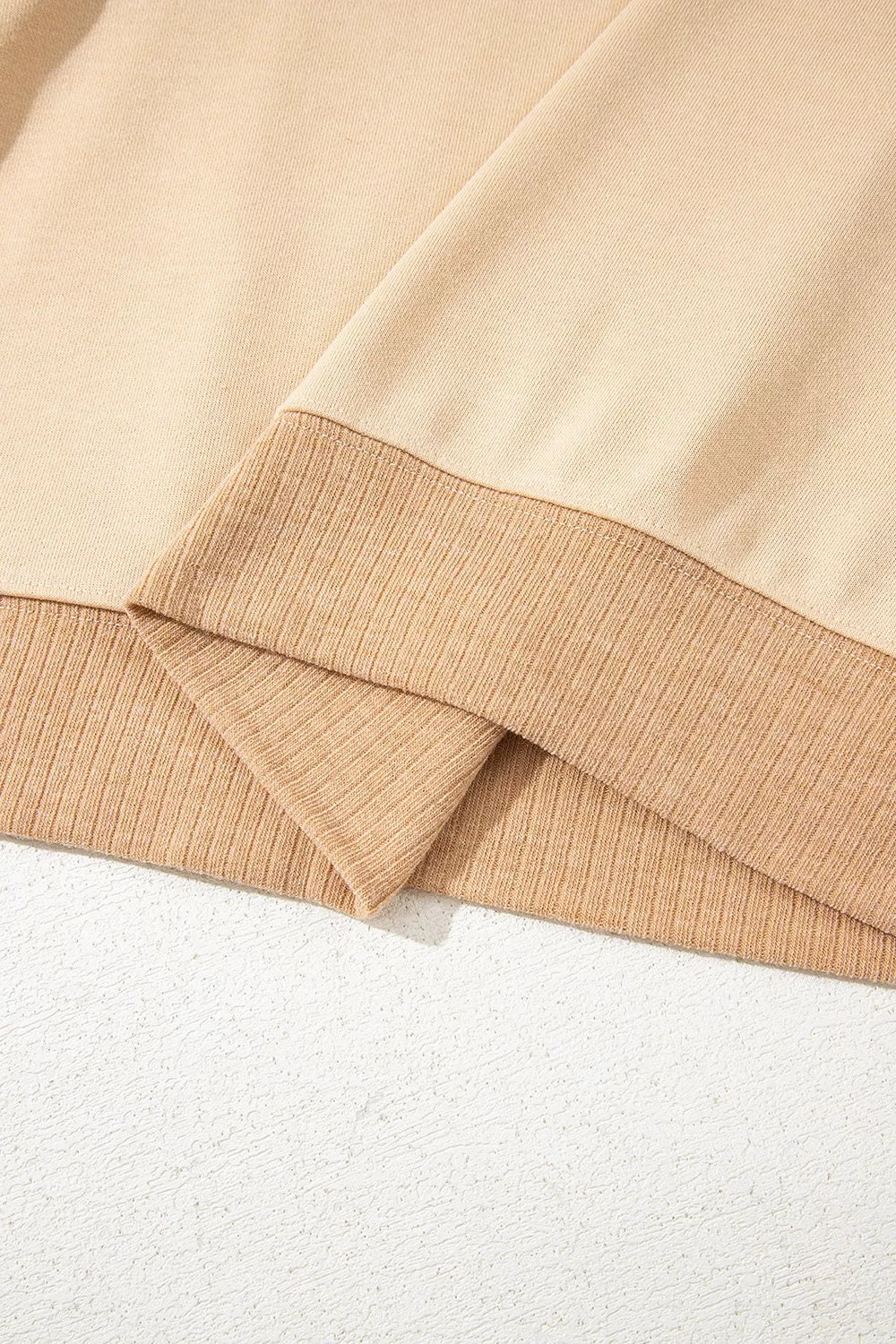 Neutral boho sweatshirt with colorful patterned contrast sleeves, ribbed hem, relaxed fit, and slightly stretchy fabric styled with denim shorts.