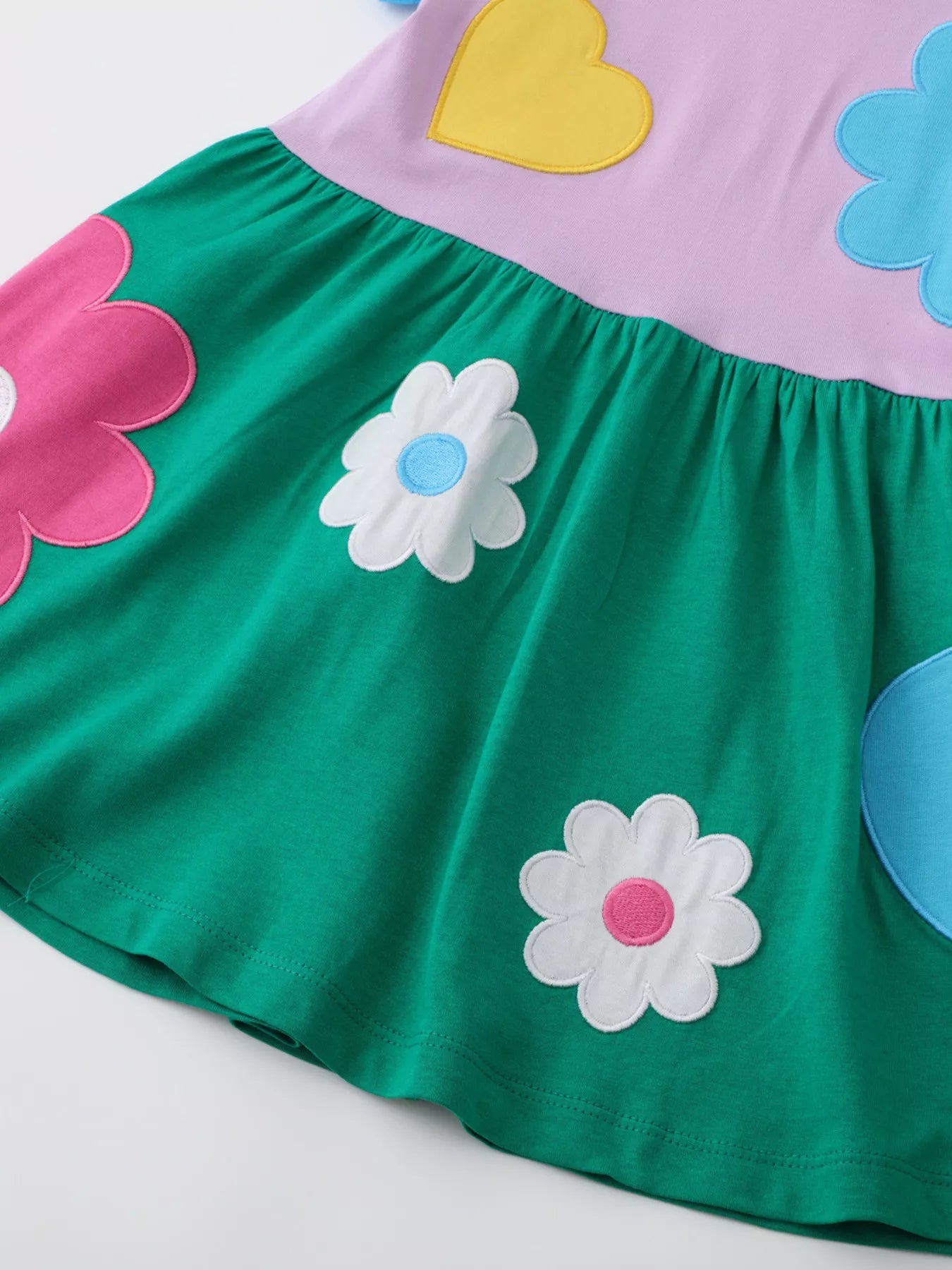 Colorful girls dress with oversized flower and heart appliqué and green skirt