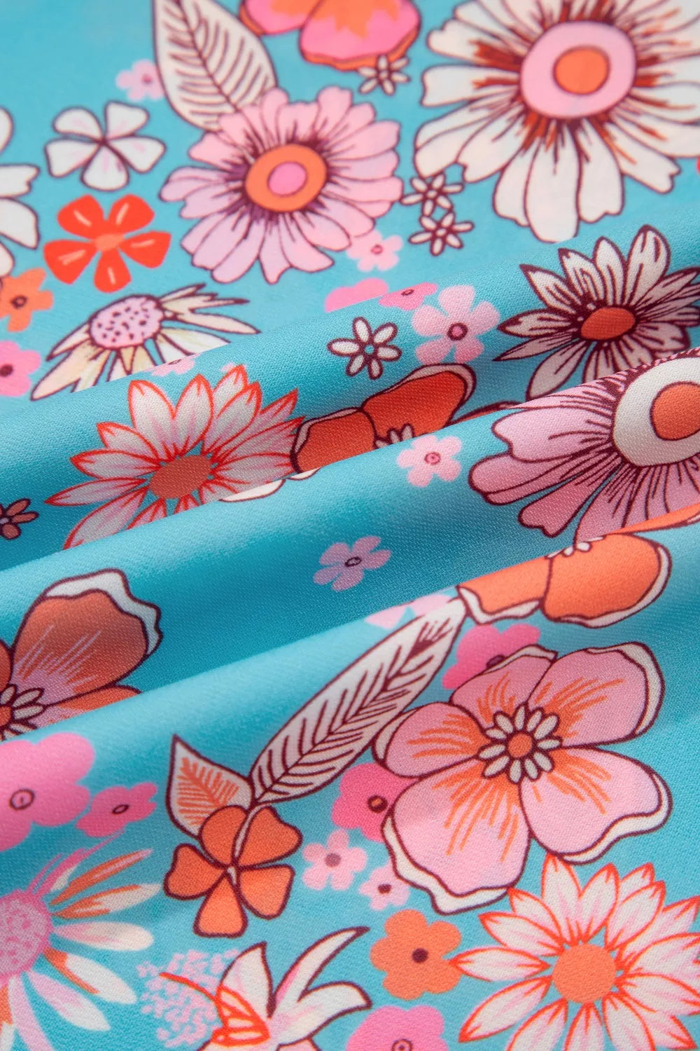 Blue floral smocked maxi dress with spaghetti straps, pink border detailing, and hidden pockets worn on the beach.