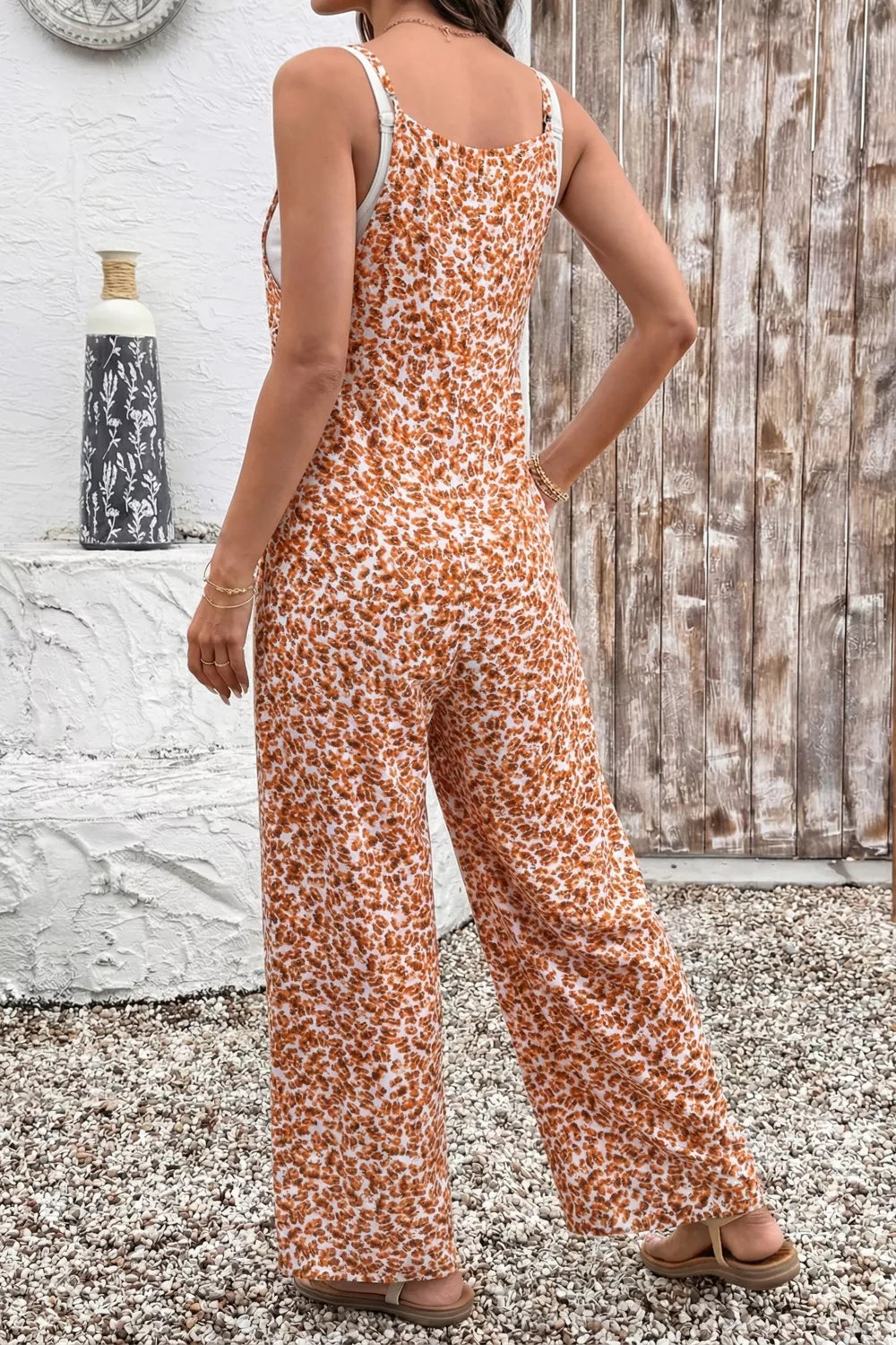 floral wide-leg jumpsuit with thin straps, relaxed flowy fit, and side pockets styled with sandals.
