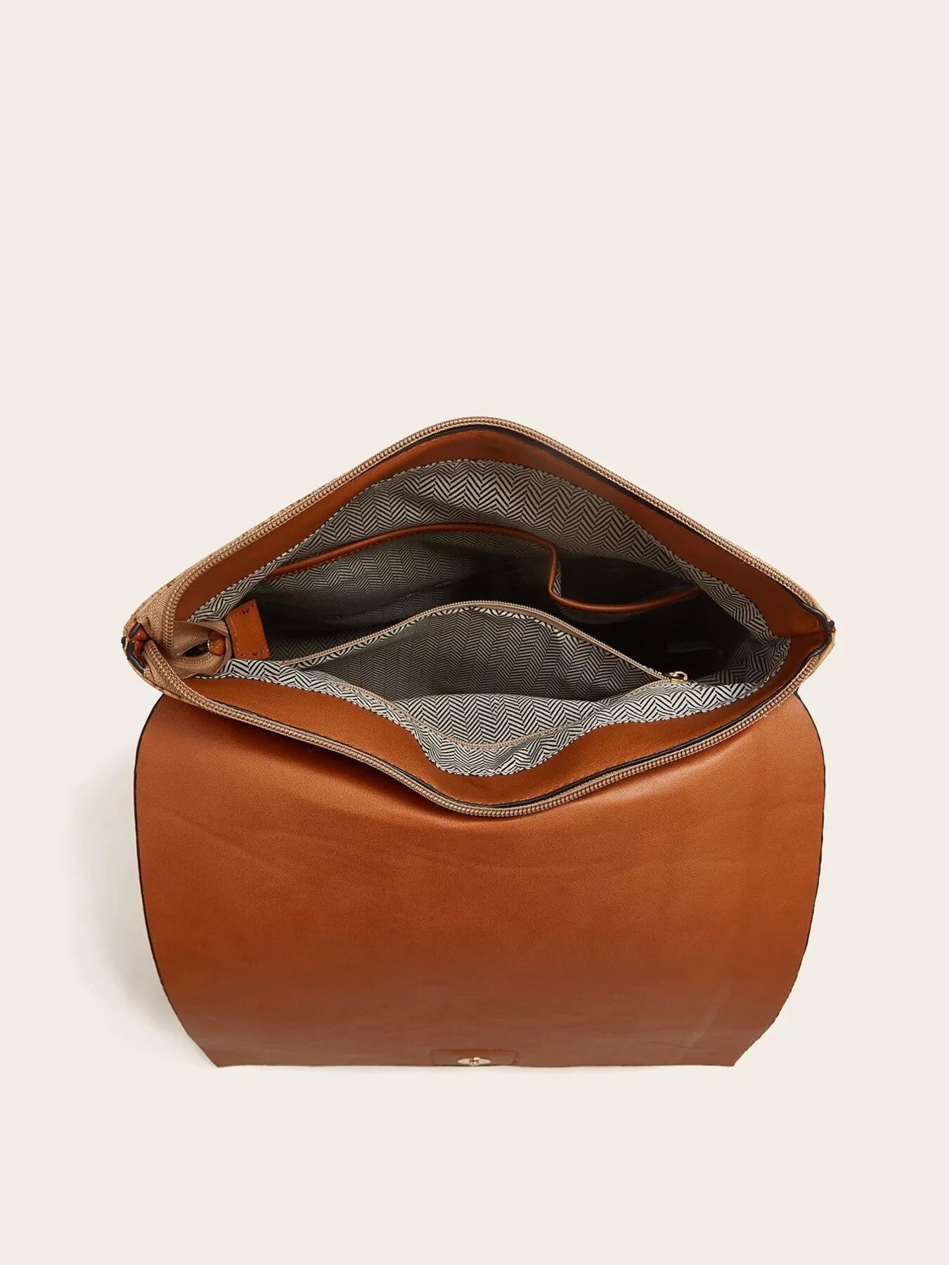 Brown leather bag with open top on a beige background