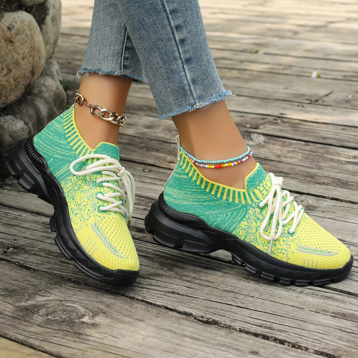Bright yellow and green knit mesh sneakers with white laces, black rubber soles, and a flat sporty design.