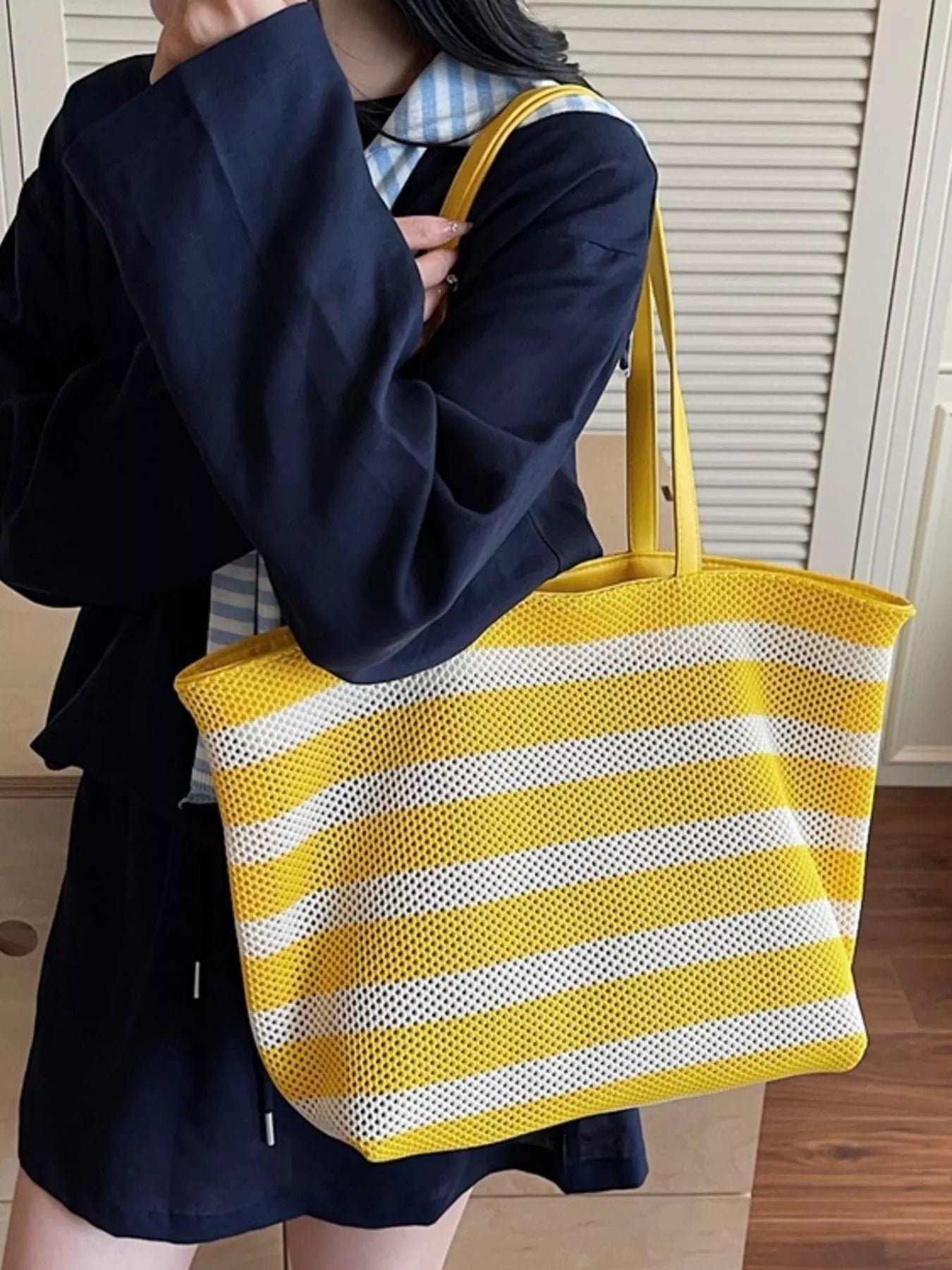 Large yellow and white striped mesh tote bag with shoulder straps, lightweight polyester material, and casual everyday styling.