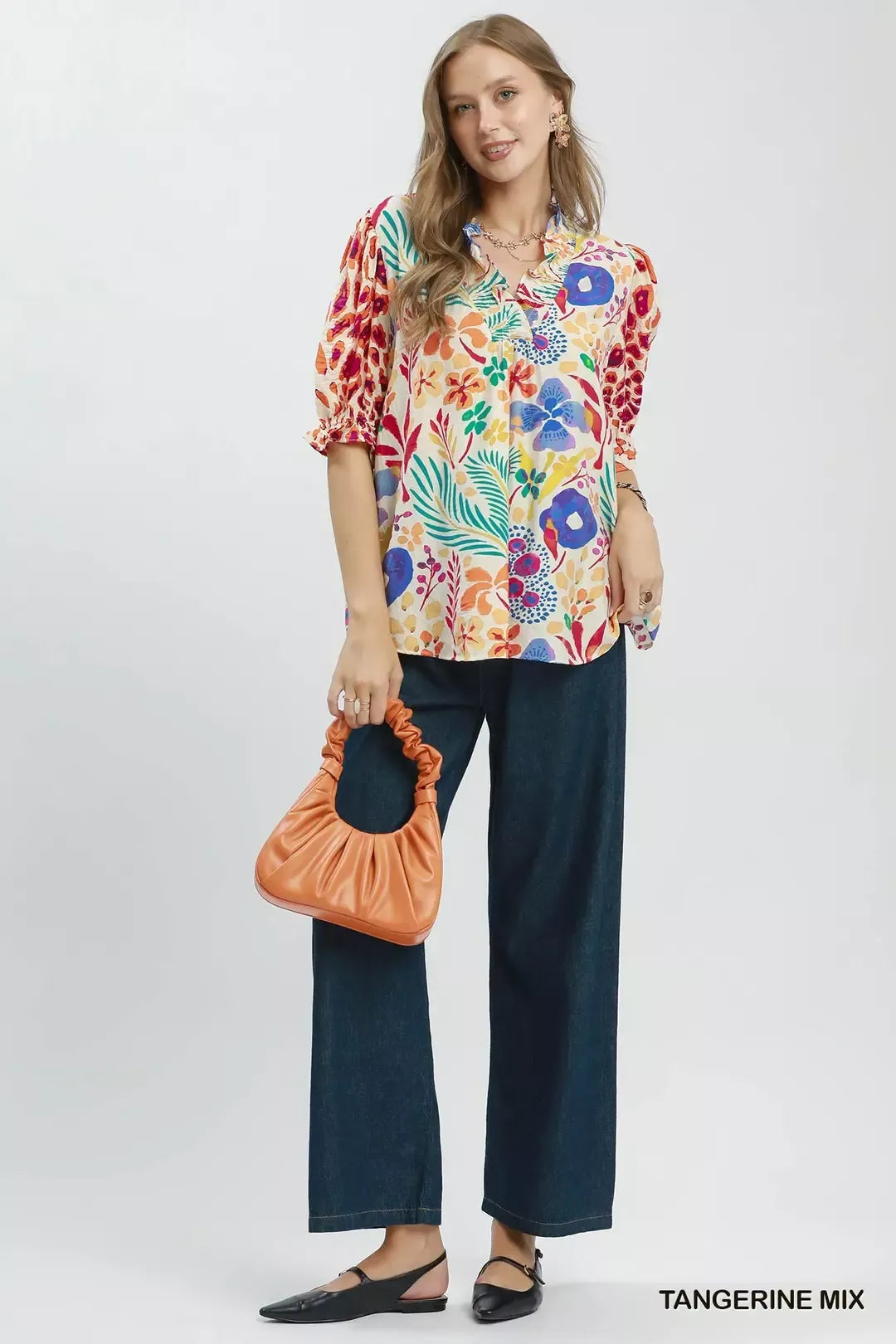 Colorful floral V-neck blouse with ruffle trim, puff sleeves, and a relaxed flowy fit styled with dark denim.