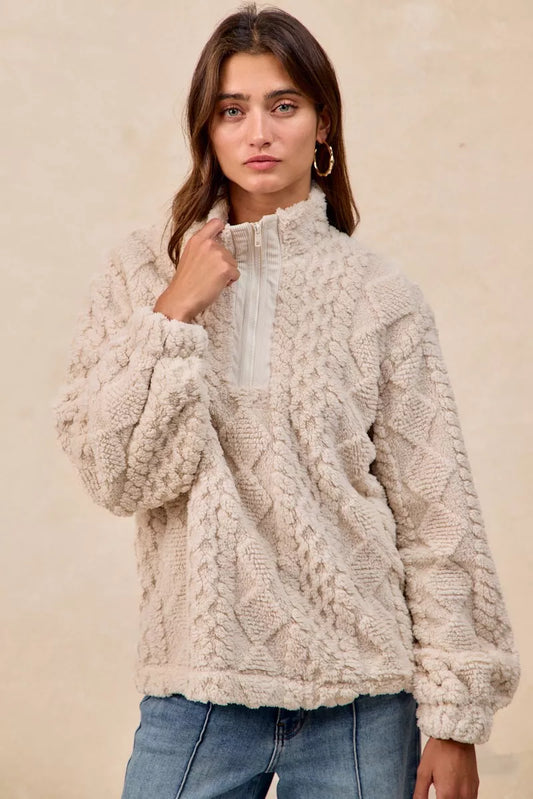 Model wearing the Vanilla Frost Cable Fleece Pullover — a cream-colored, cable-textured fleece half-zip sweater with a relaxed, cozy fit.