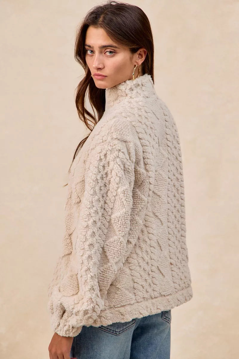 Model wearing the Vanilla Frost Cable Fleece Pullover — a cream-colored, cable-textured fleece half-zip sweater with a relaxed, cozy fit.