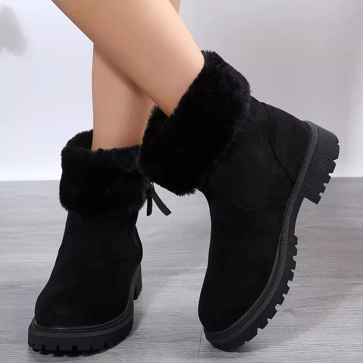 Women’s suede winter boots with plush fur cuff detail and mid-height rubber sole.