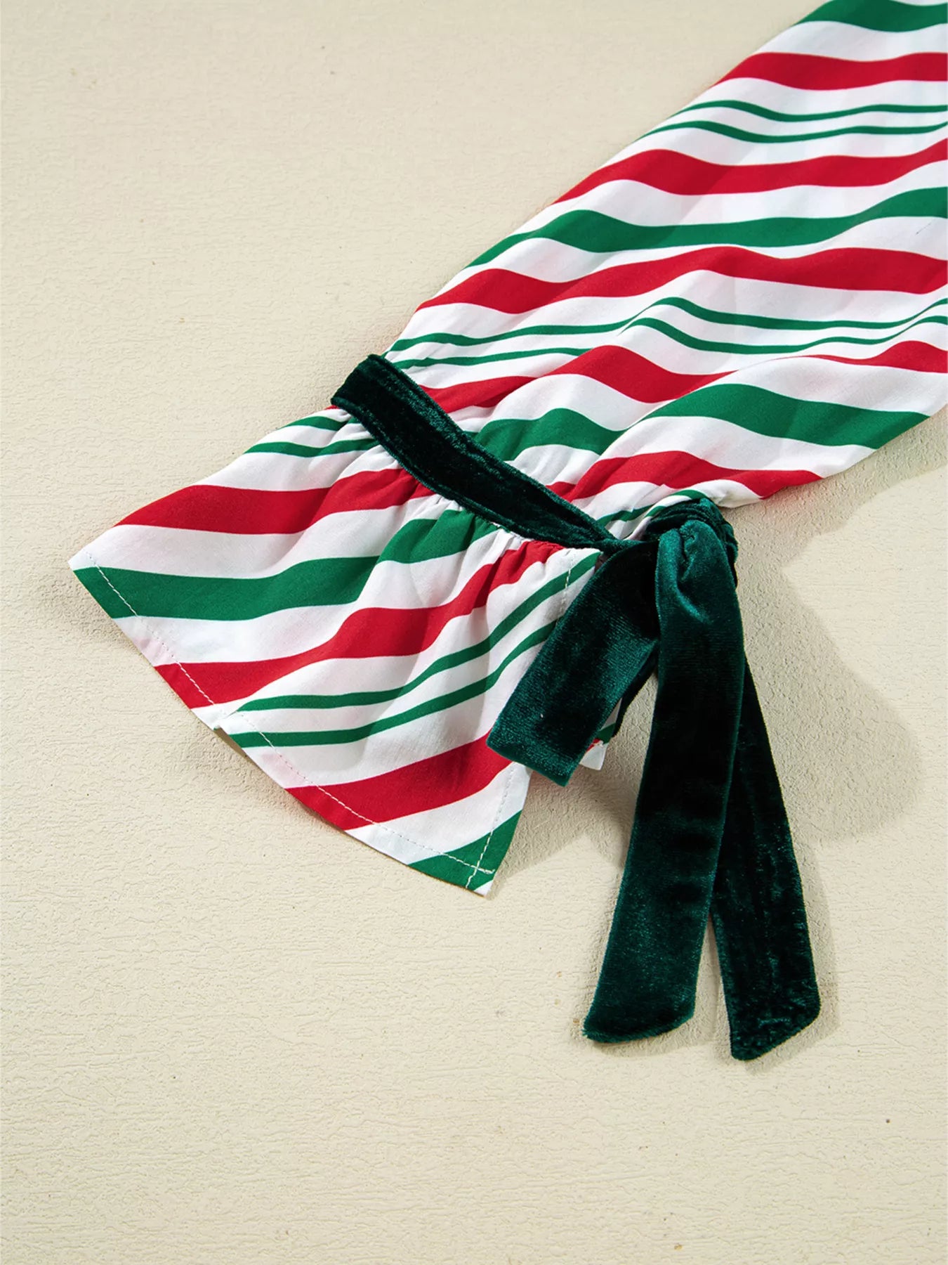 Festive striped two-piece pajama set with velvet waist tie and long sleeves.