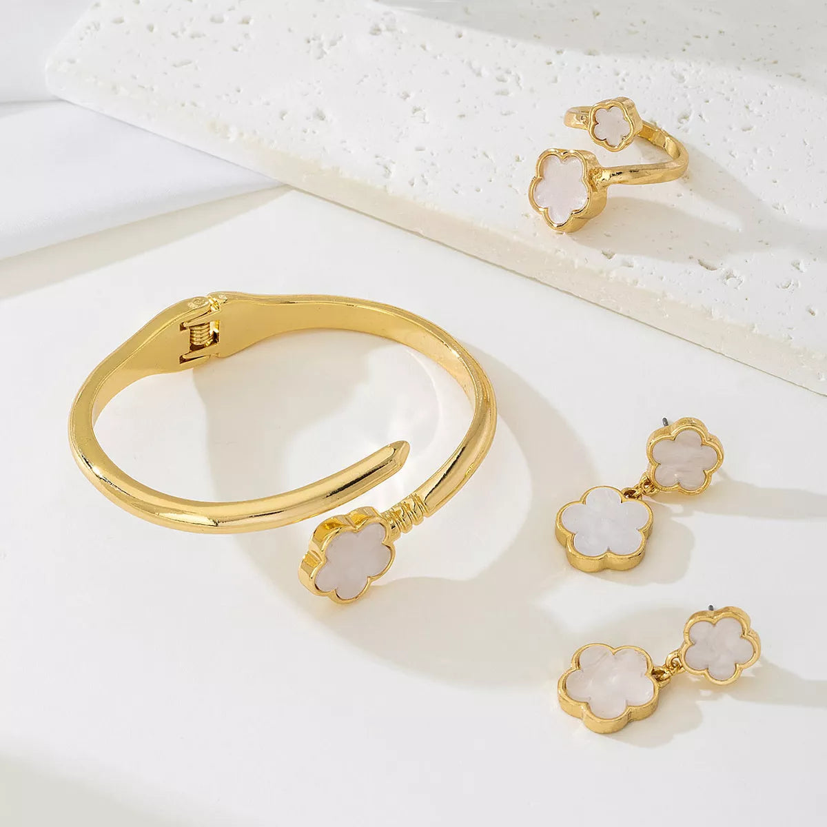 Matching gold-plated white clover jewelry set including earrings, bracelet, and ring — elegant minimalist design.