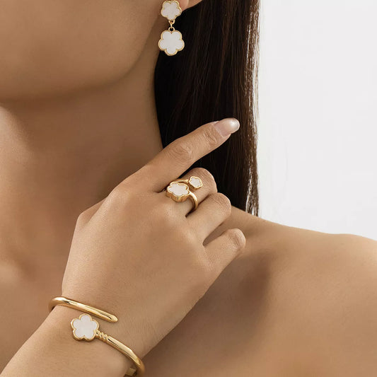 Model wearing matching gold-plated white clover jewelry set including earrings, bracelet, and ring — elegant minimalist design.