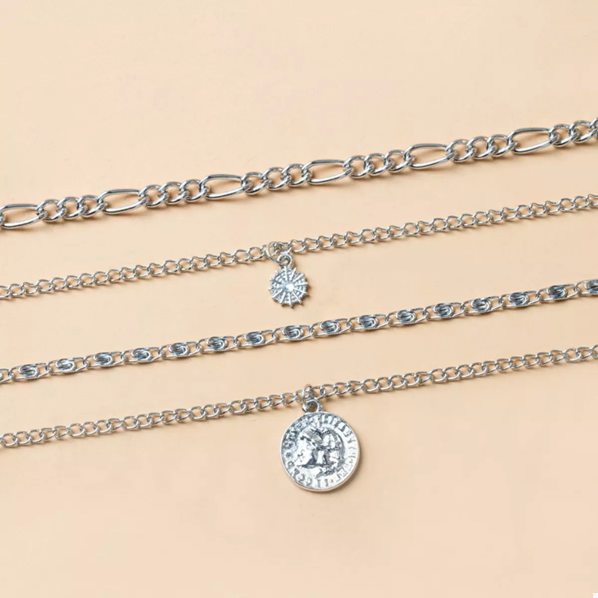 Celestial layered necklace stack with vintage coin charm and radiant sun pendant