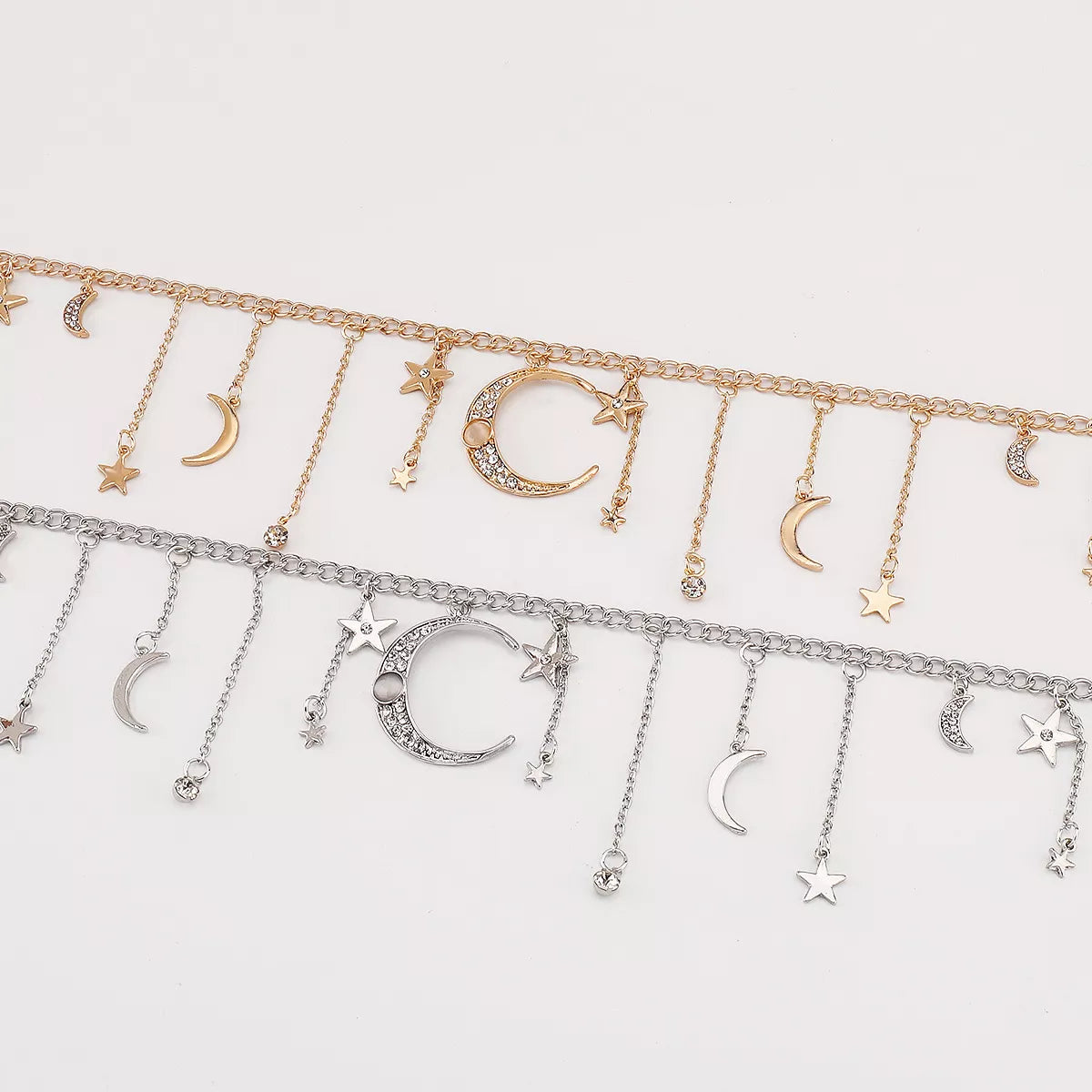 Gold and silver celestial necklaces featuring dangling moon, star, and rhinestone charms arranged on chain links.