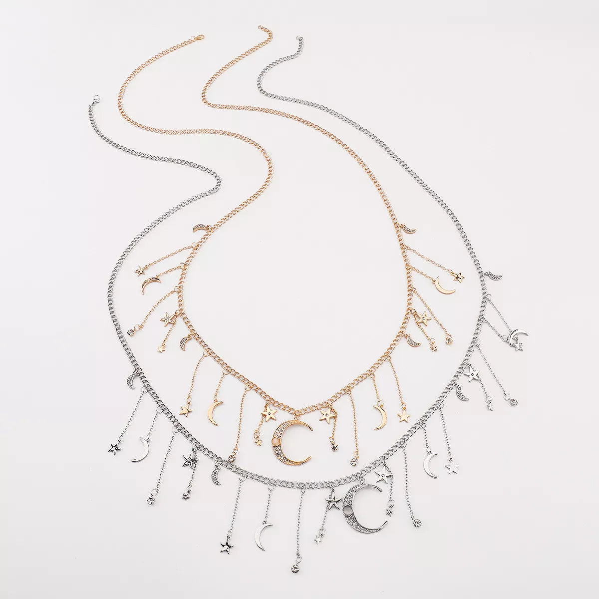 Gold and silver celestial necklaces featuring dangling moon, star, and rhinestone charms arranged on chain links.