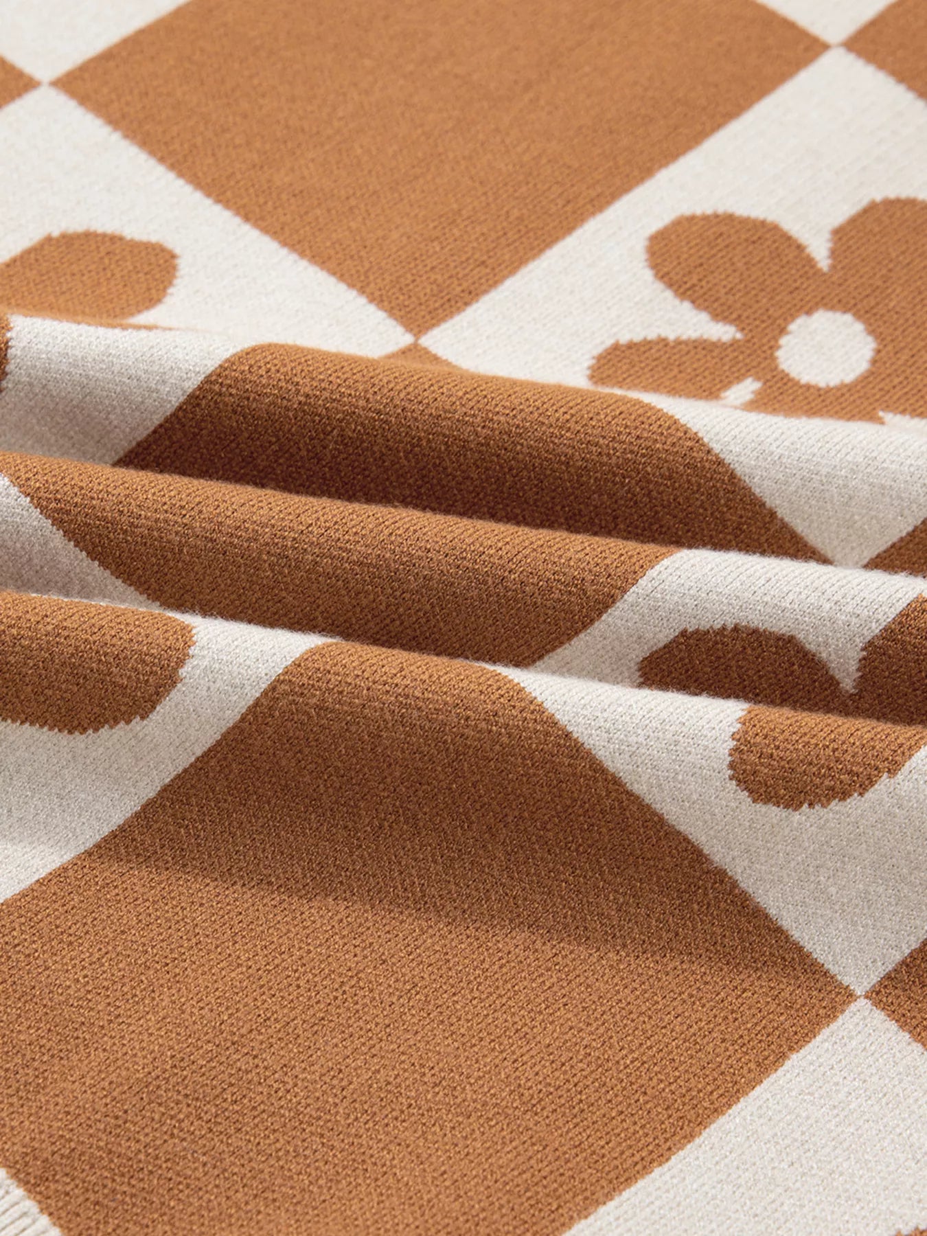 Brown and cream checkerboard henley sweater with daisy floral pattern