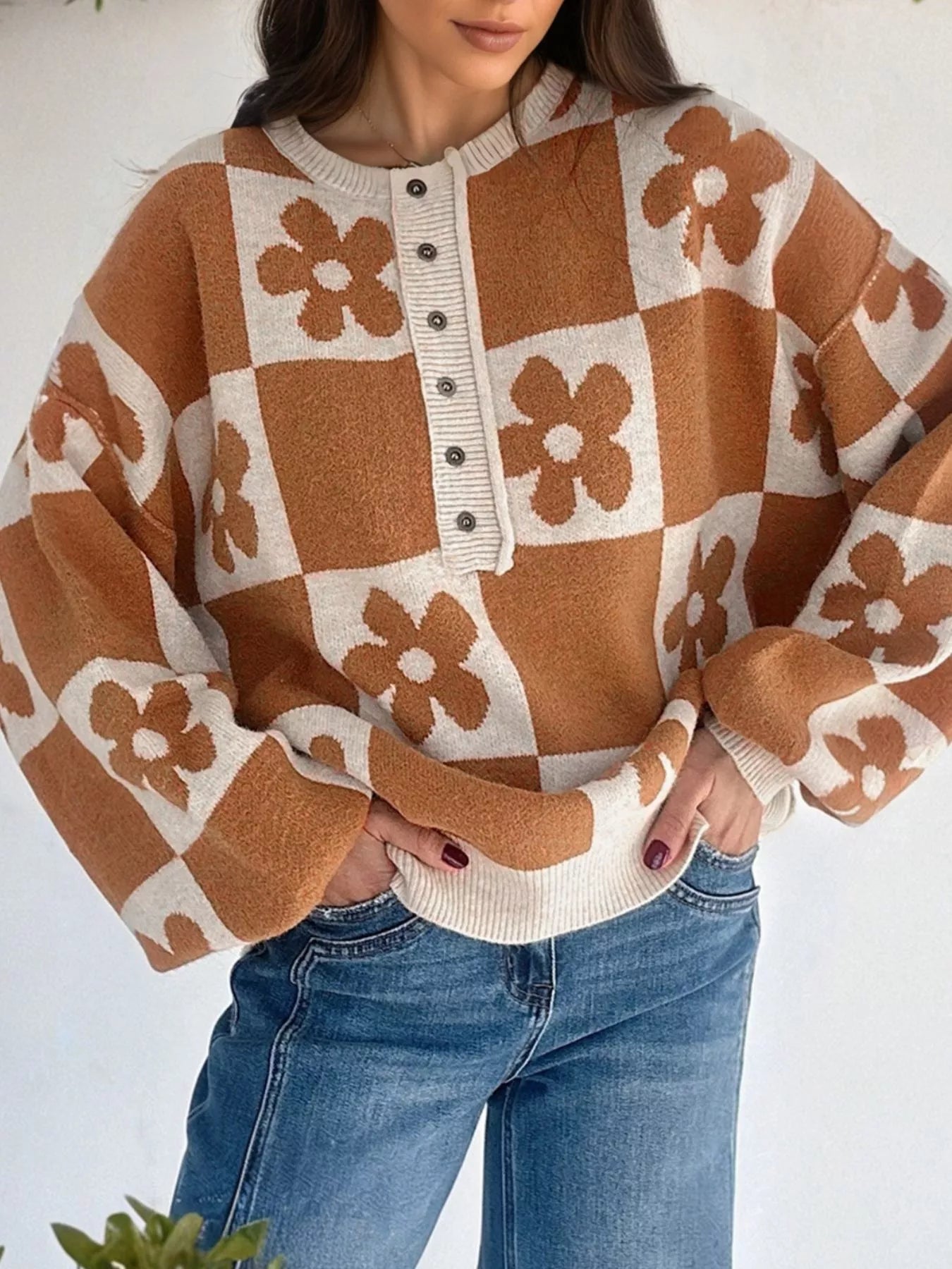 Brown and cream checkerboard henley sweater with daisy floral pattern on model with jeans