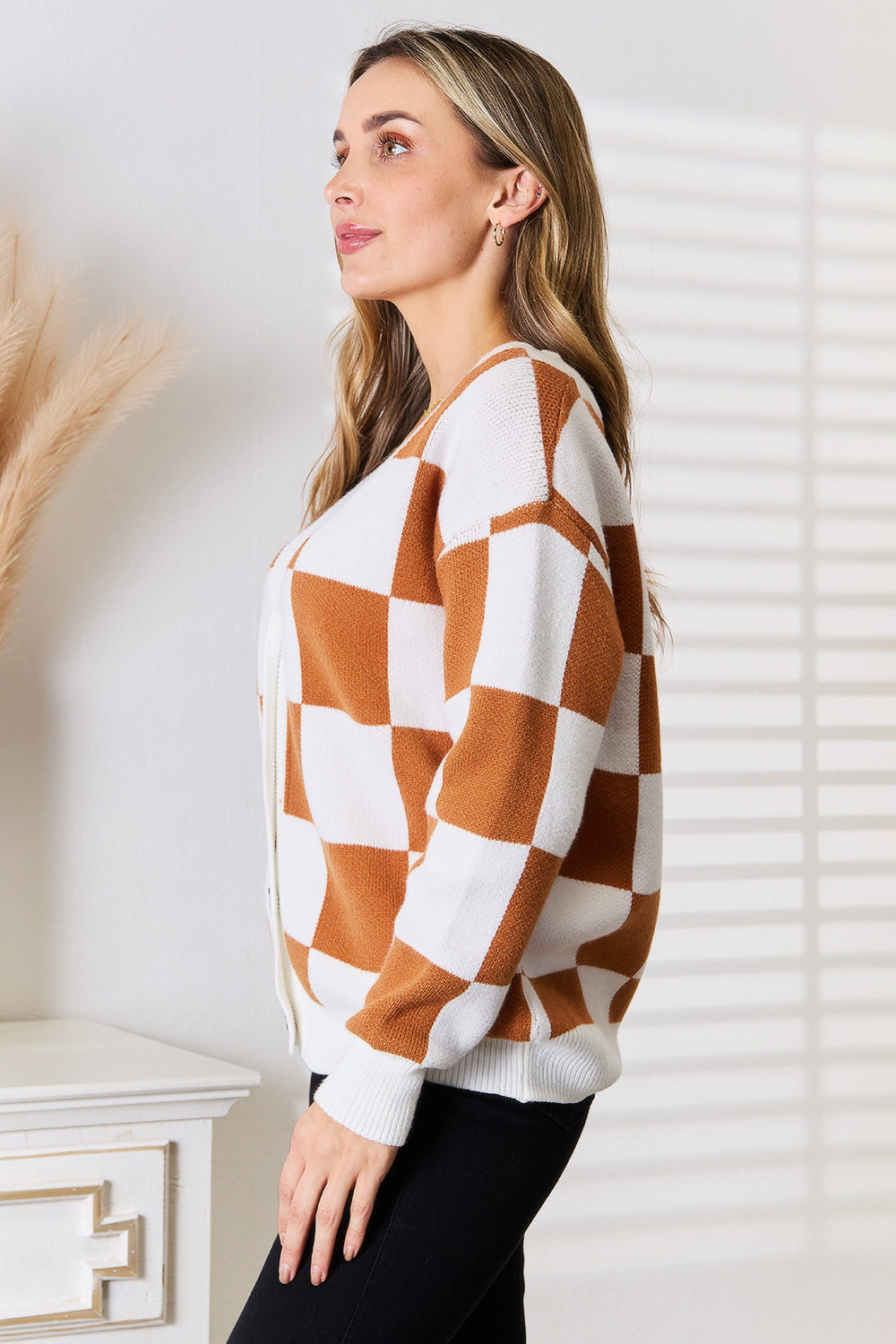 woman wearing a cinnamon and ivory checkered V-neck button-up cardigan with dropped shoulders.