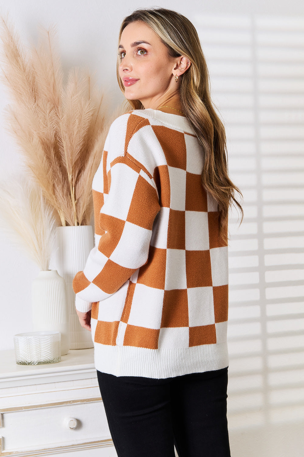 woman wearing a cinnamon and ivory checkered V-neck button-up cardigan with dropped shoulders.