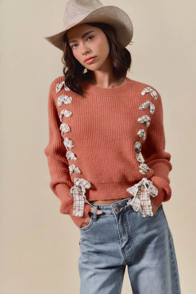Woman wearing a rust ribbed knit sweater with plaid bows and side tie accents – cozy rustic fall fashion from A Whimsical Affair.