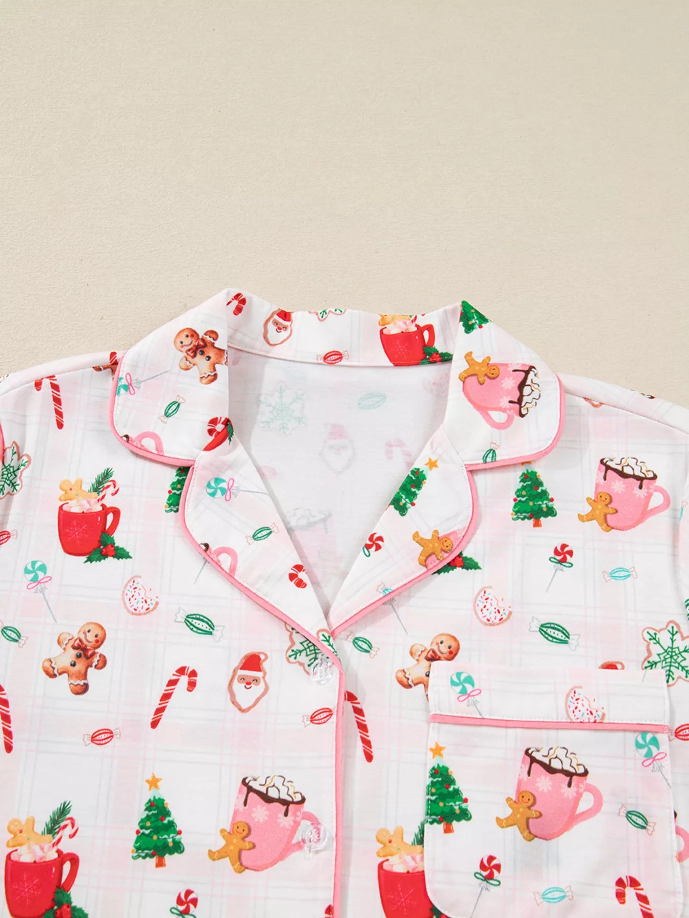 Close-up of holiday printed pajama pants featuring candy canes, cocoa mugs, gingerbread cookies, and Santa motifs.