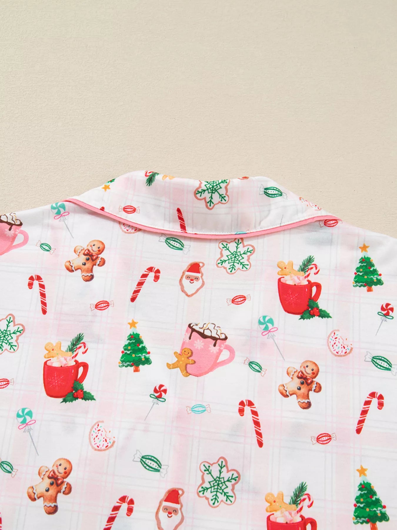 Close-up of holiday printed pajama pants featuring candy canes, cocoa mugs, gingerbread cookies, and Santa motifs.