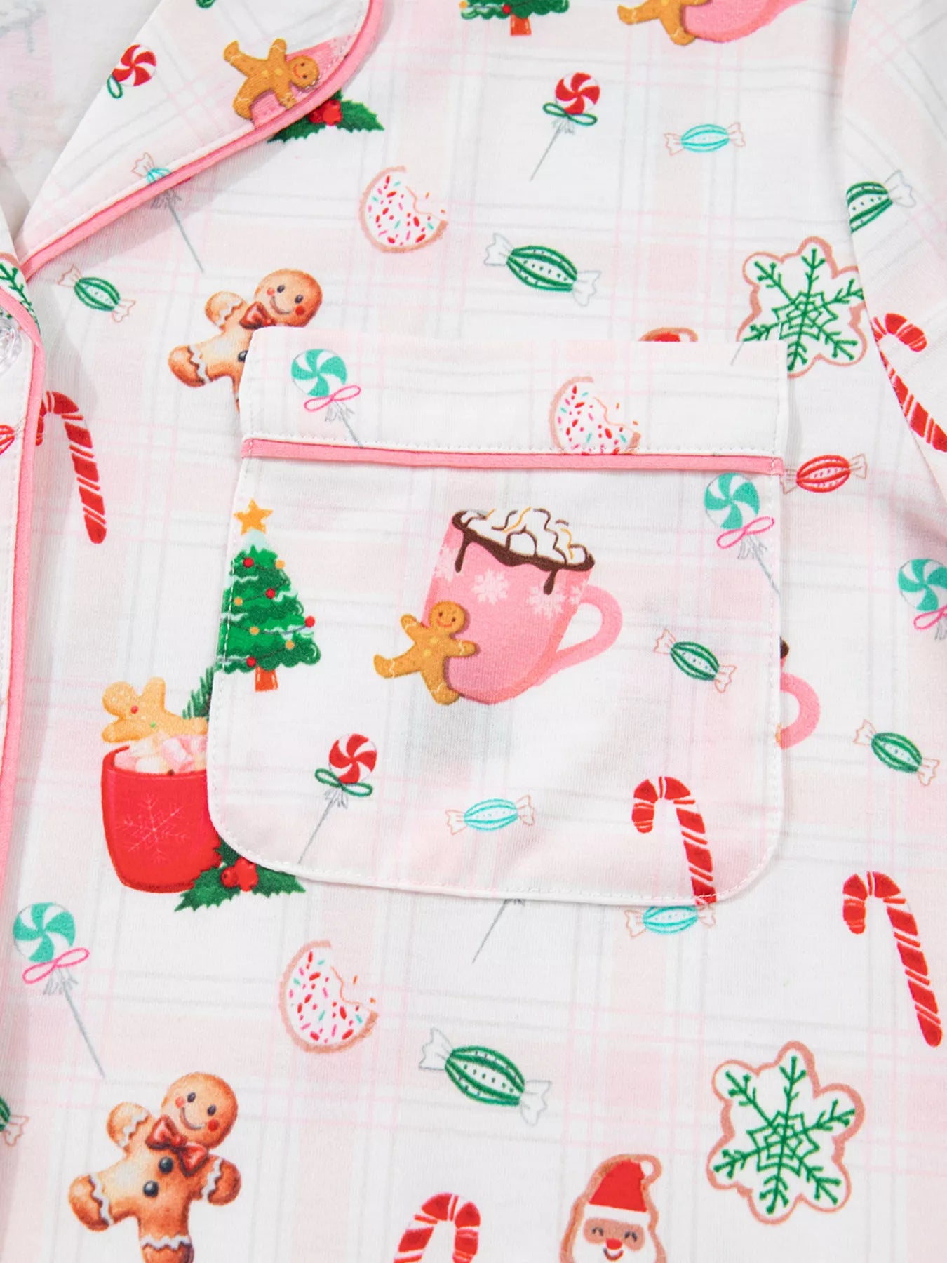 Close-up of holiday printed pajama pants featuring candy canes, cocoa mugs, gingerbread cookies, and Santa motifs.