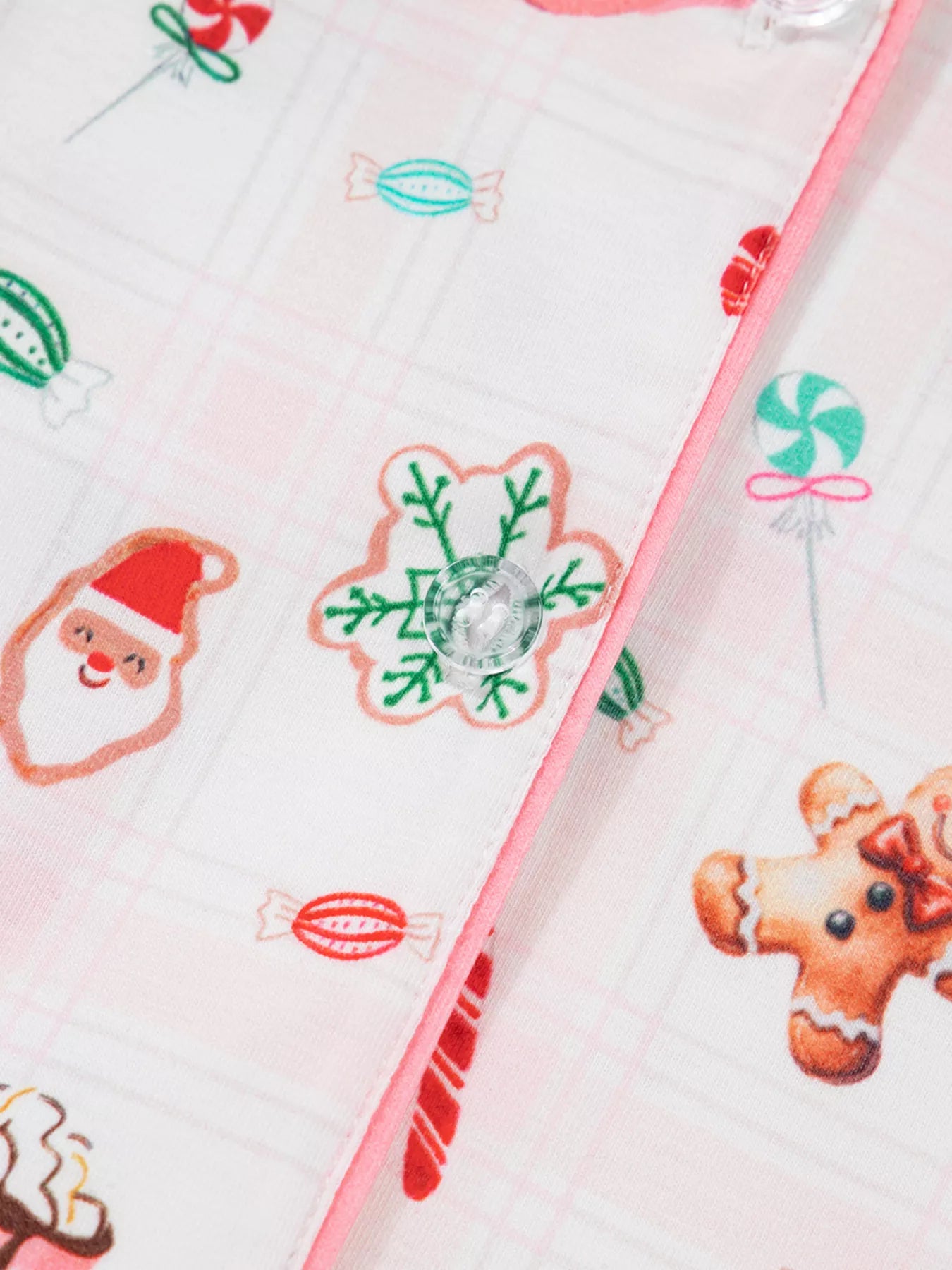 Close-up of holiday printed pajama pants featuring candy canes, cocoa mugs, gingerbread cookies, and Santa motifs.