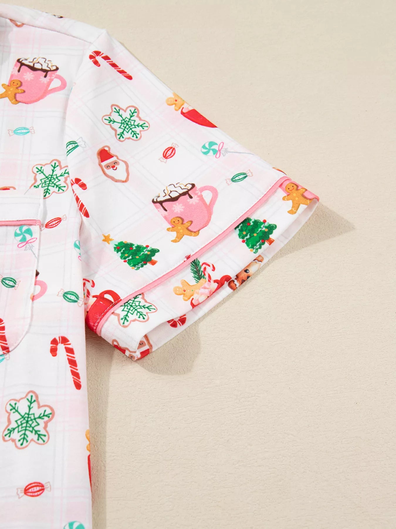 Close-up of holiday printed pajama pants featuring candy canes, cocoa mugs, gingerbread cookies, and Santa motifs.