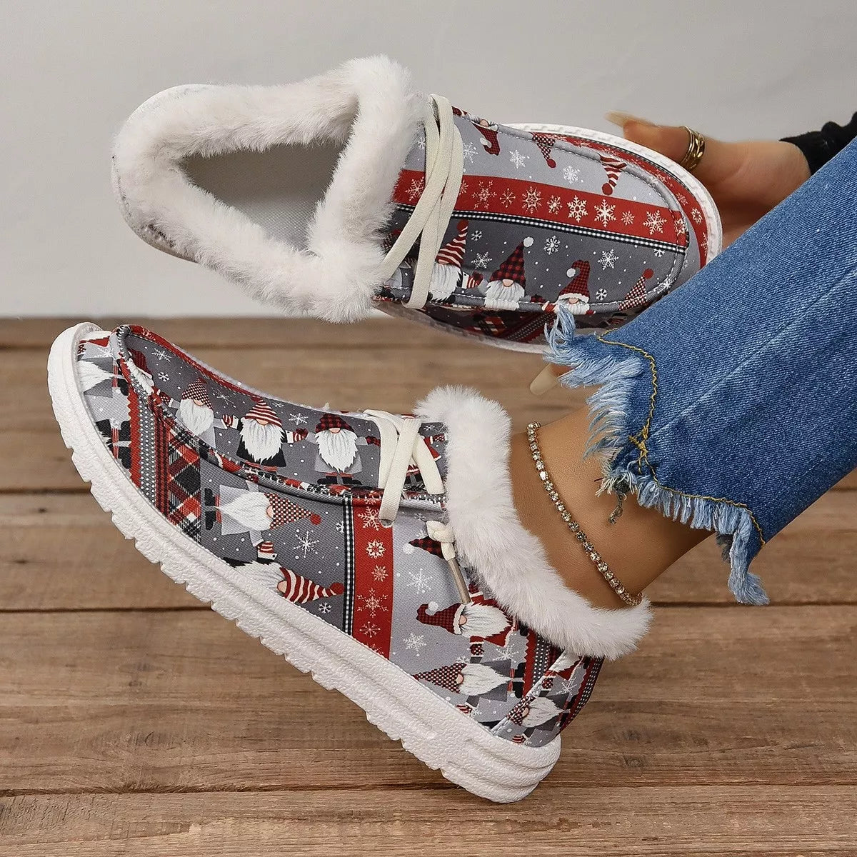 Close-up of gray and red Christmas gnome print loafers with white faux-fur lining worn with frayed hem jeans.