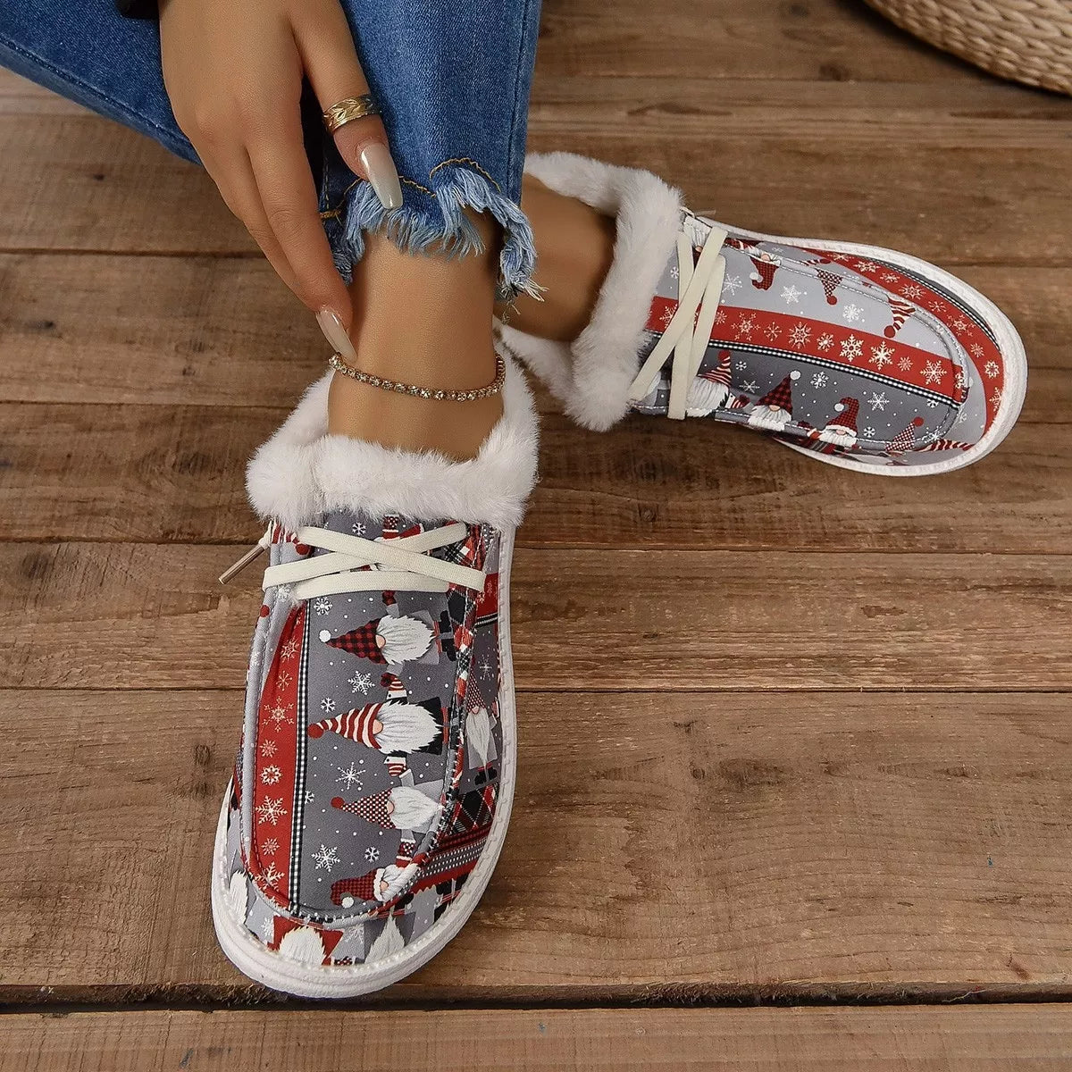 Close-up of gray and red Christmas gnome print loafers with white faux-fur lining worn with frayed hem jeans.