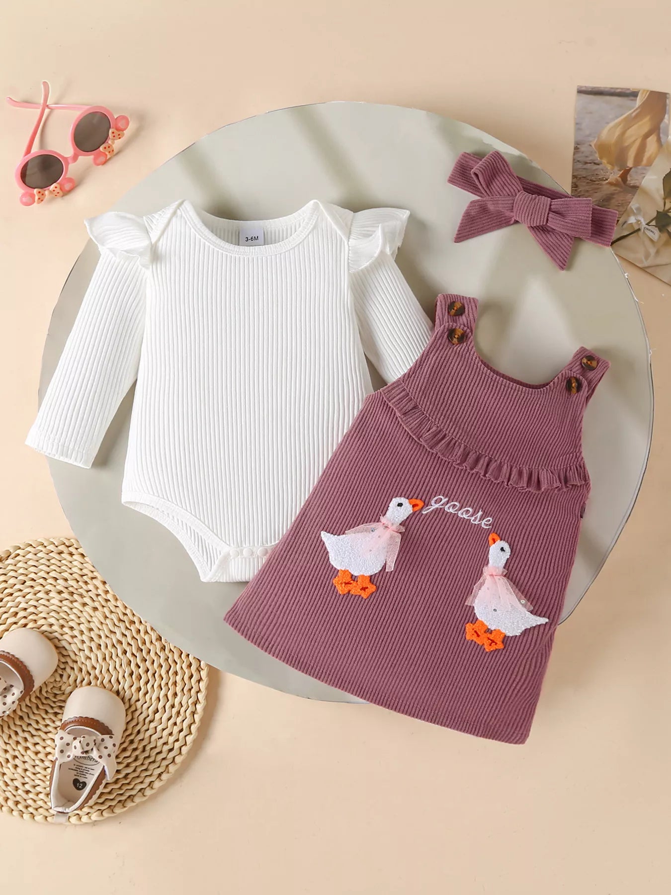 2-piece outfit with mauve corduroy jumper dress featuring embroidered geese and a white long-sleeve top, styled with matching bow and accessories.